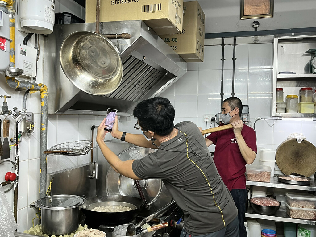 Jook Guan stirs the porridge mix while Raphael tries to get the best camera angle