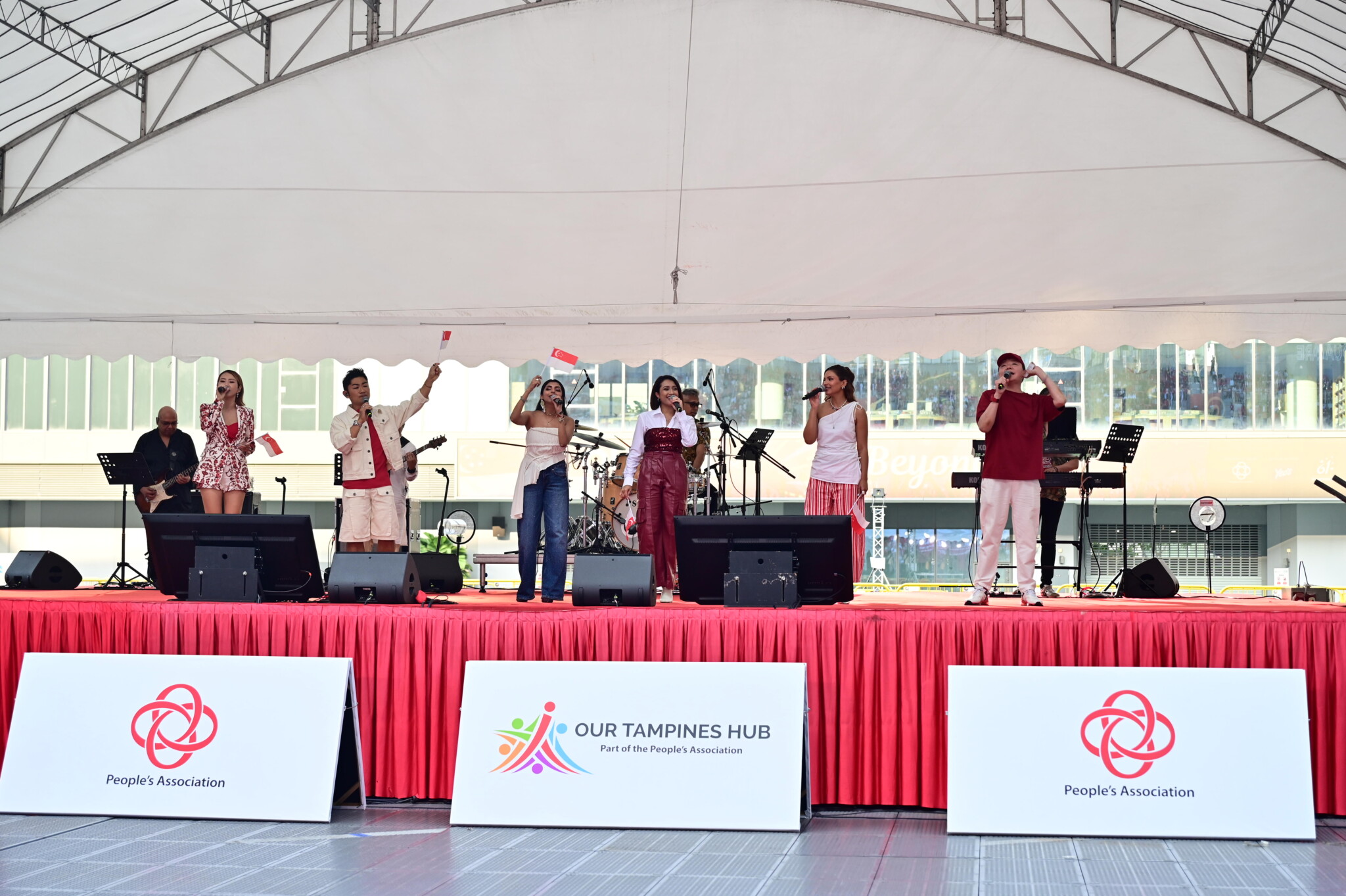 Band performing on stage at Our Tampines Hub with People's Association signage