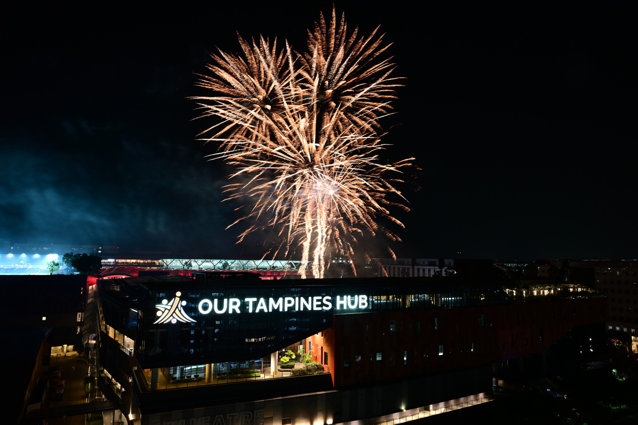 Fireworks bursting over the illuminated Our Tampines Hub building