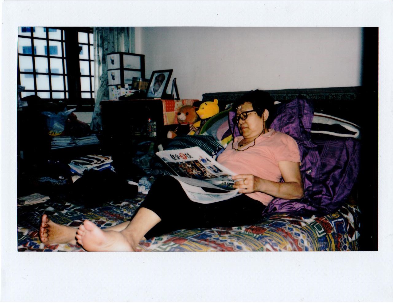 A woman lying on a bed reading a newspaper