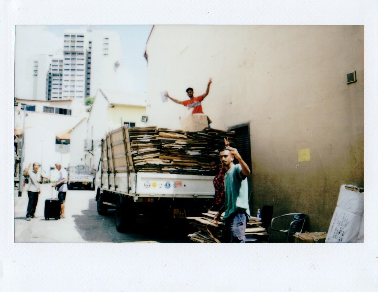 A truck stacked with flattened cardboard in a small street
