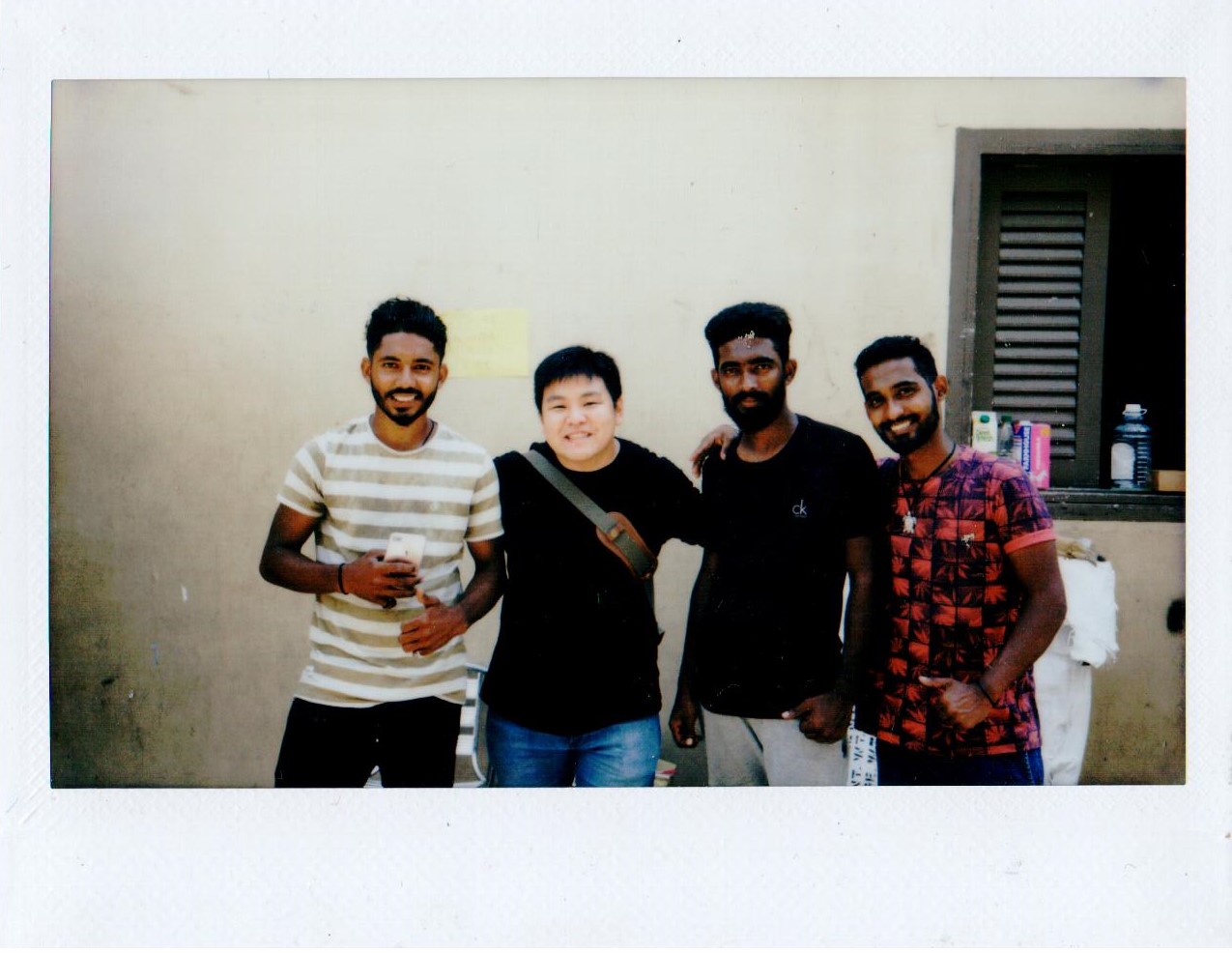 Four men smiling together against a wall