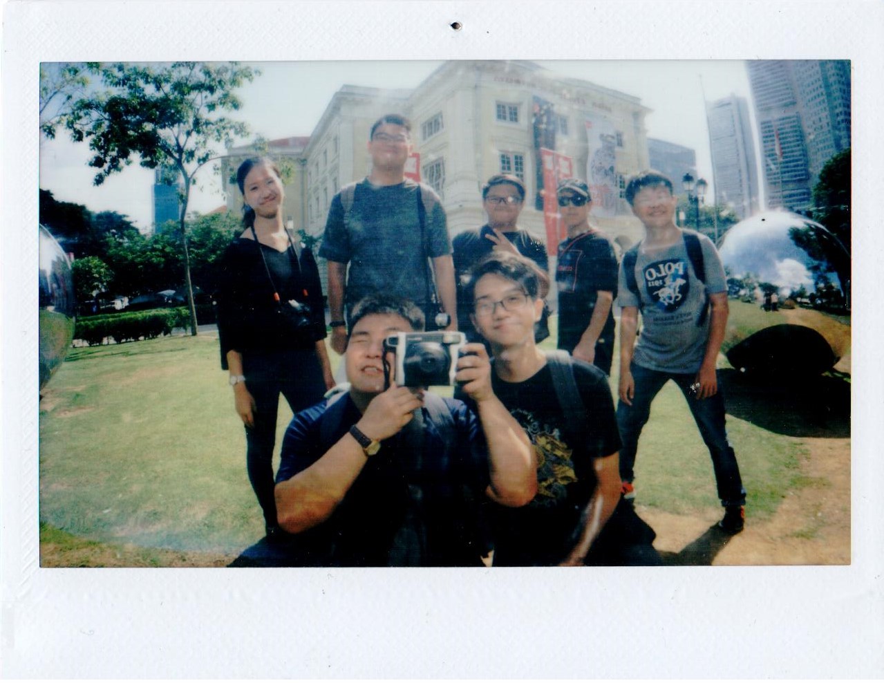 A group on a lawn, one person holding a camera to their face