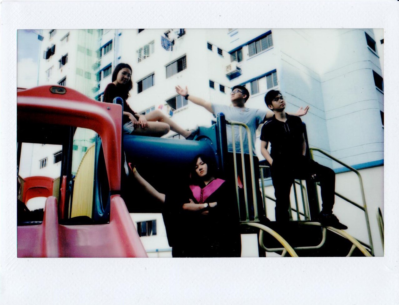 A group posing on a playground slide in front of flats