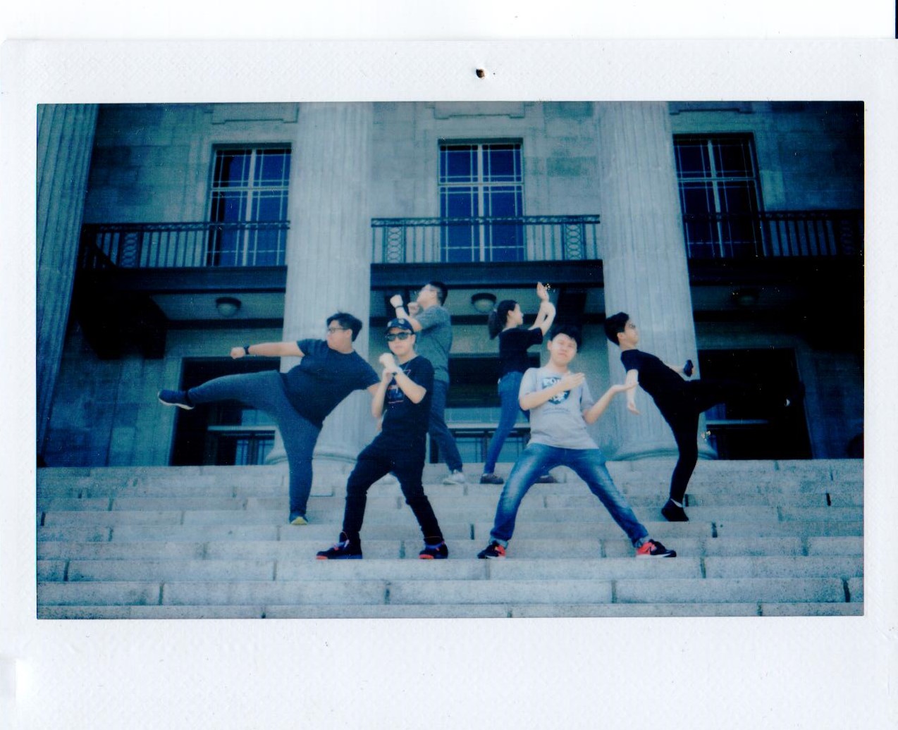 A group of people striking poses on the steps of a stone building