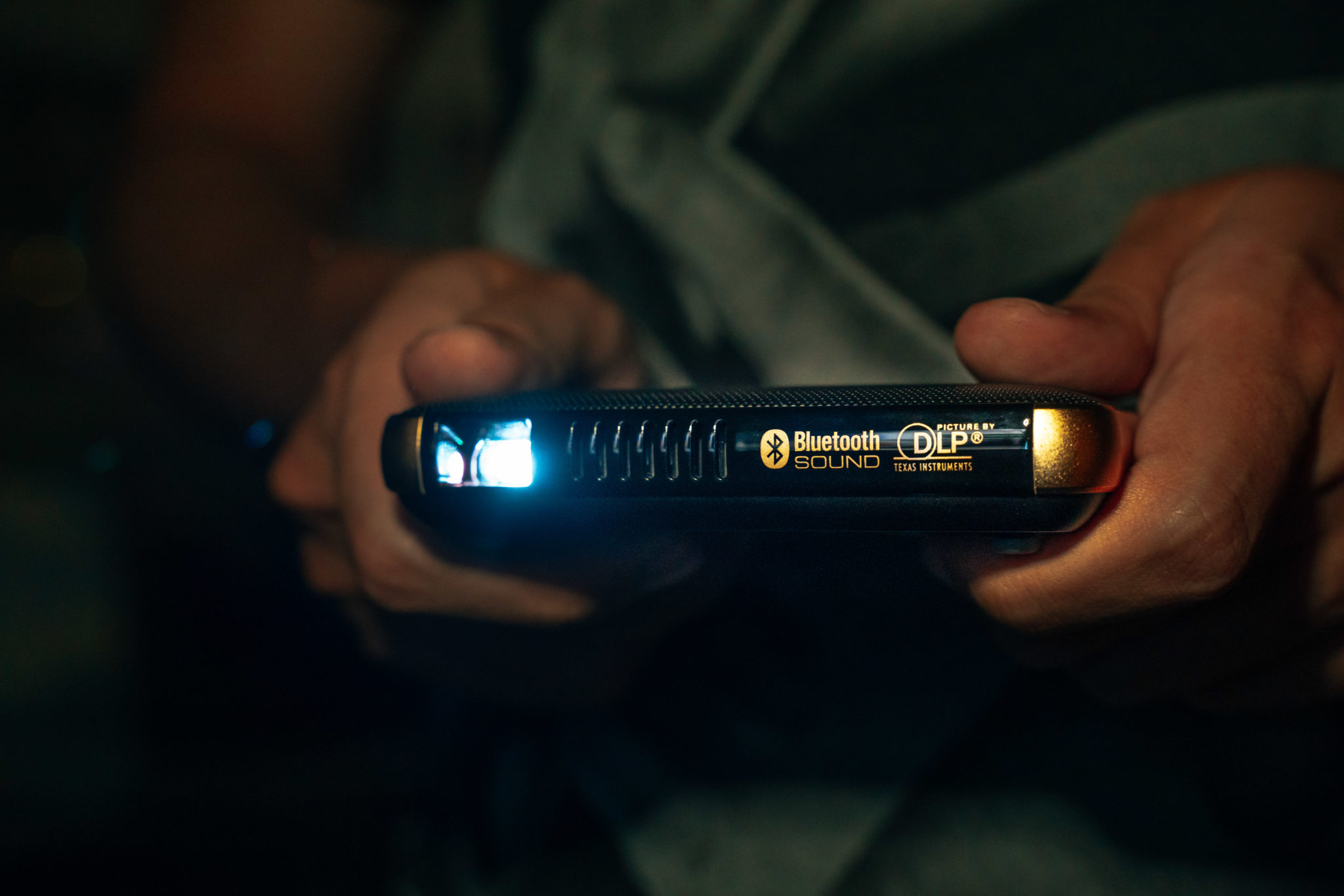 The Canon Rayo S1 held in two hands with its light shining in a dark room
