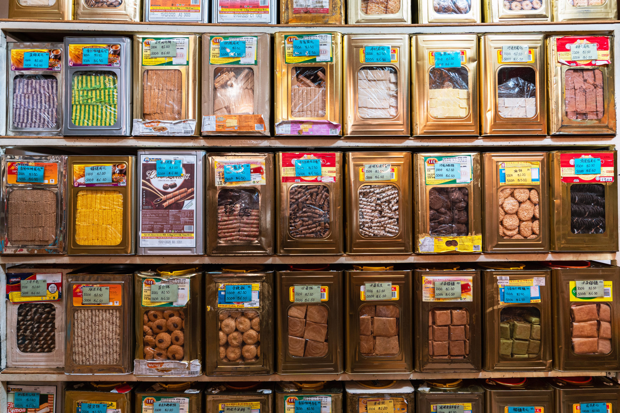 A shop wall of biscuit tins in rows