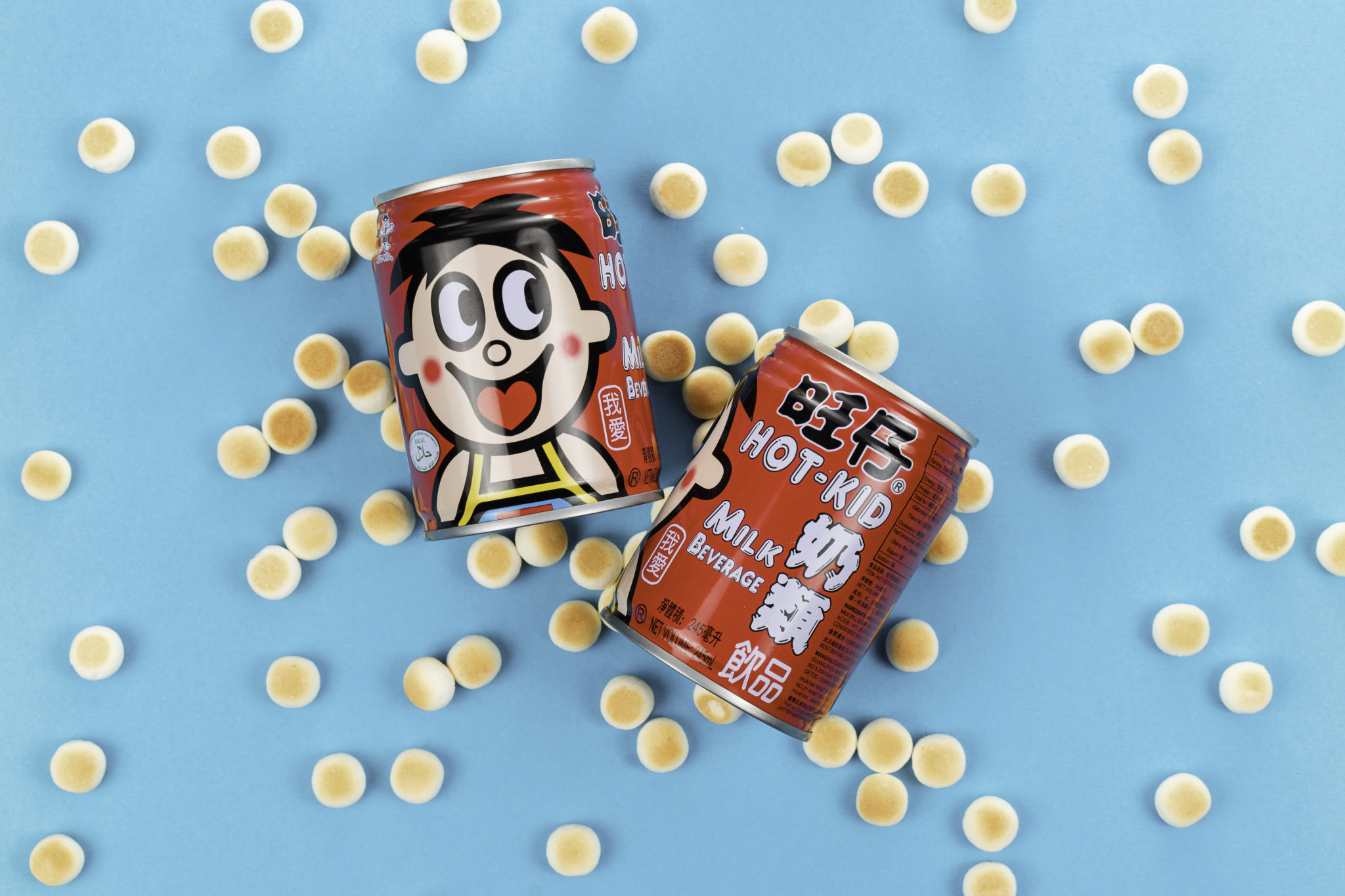 Wang Zai cans surrounded by small round biscuits on a blue background