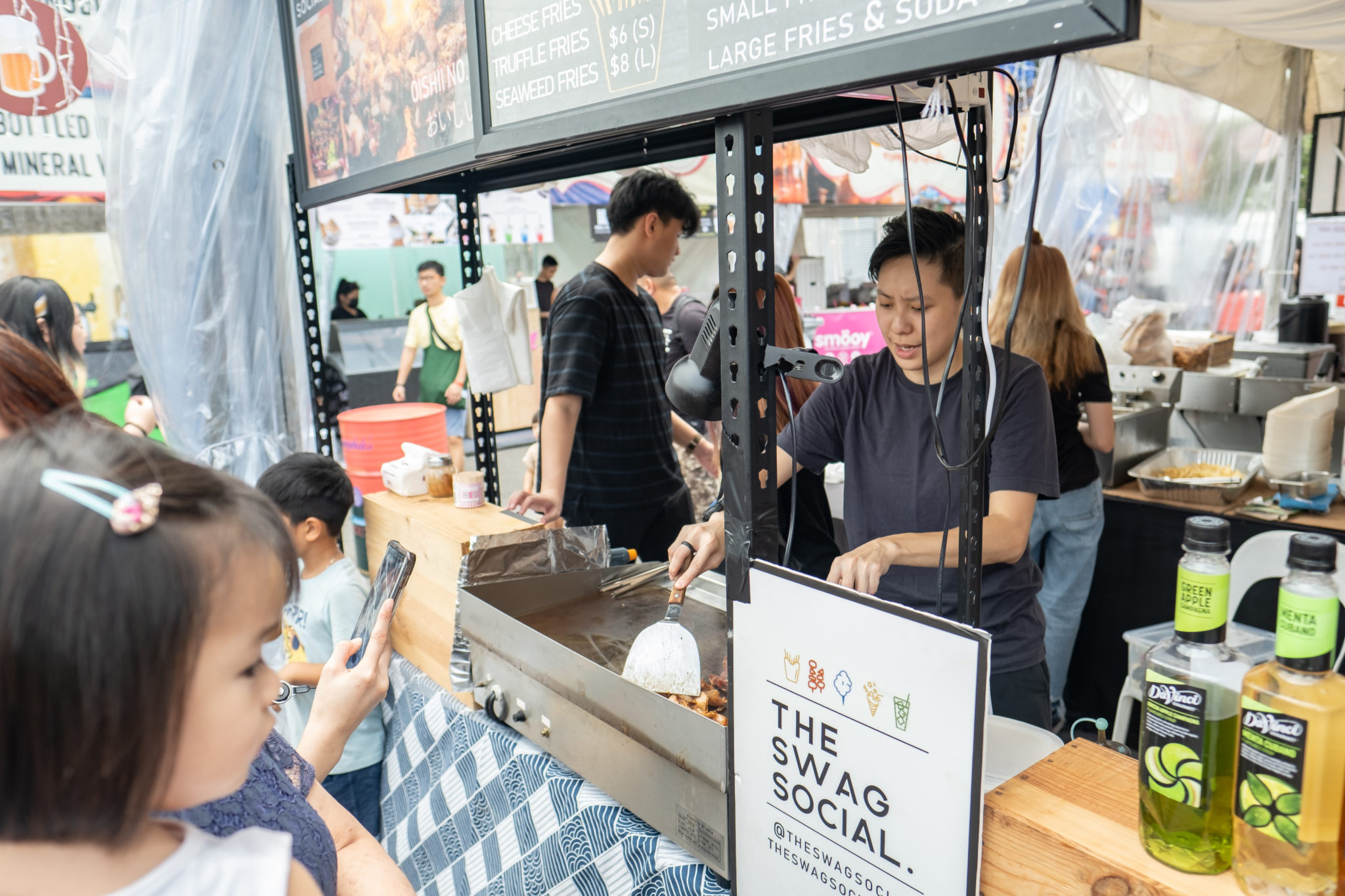 A food stall in the Escapade Festival Village with customers waiting