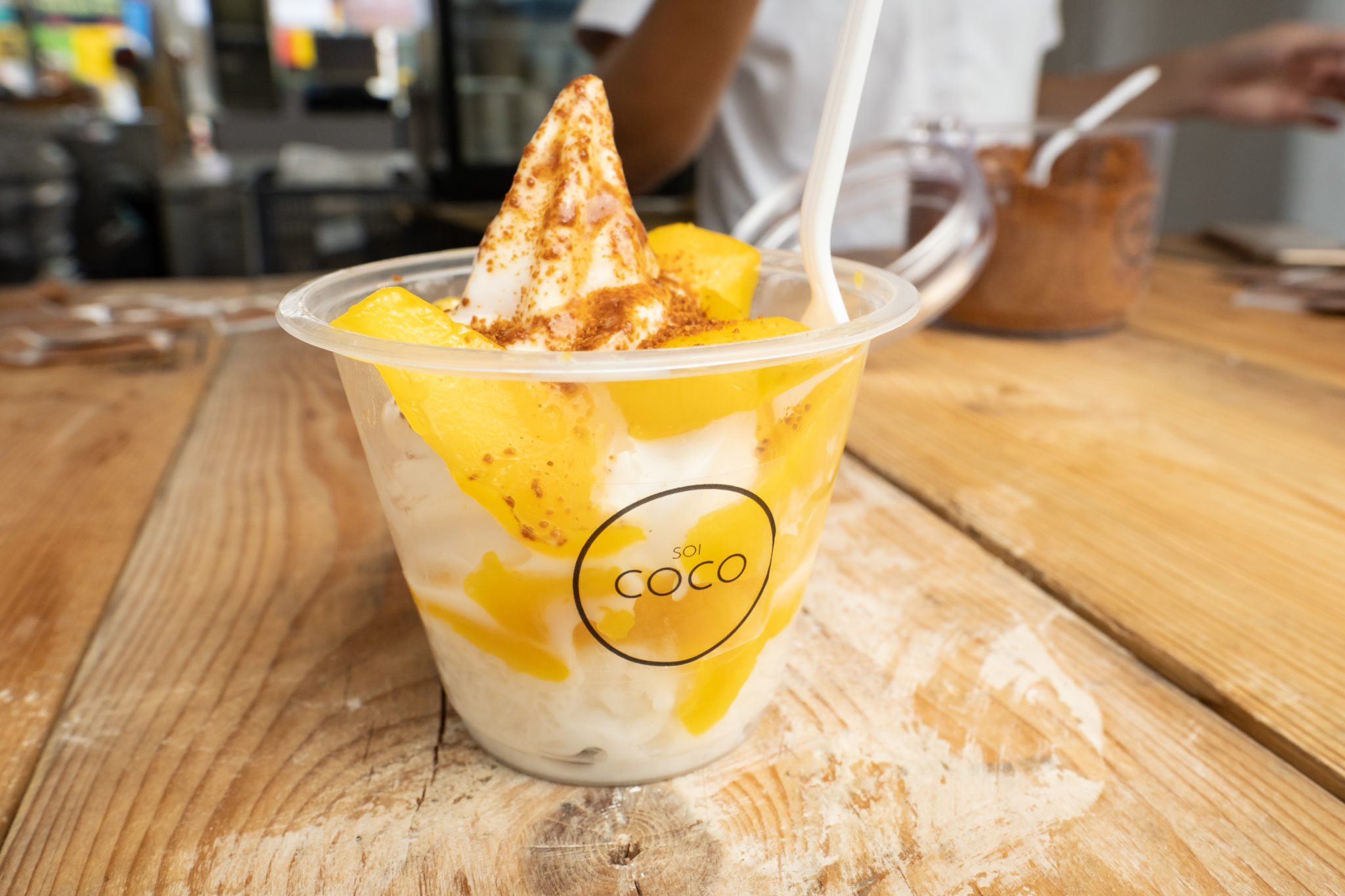 A cup of mango sticky rice topped with coconut soft serve