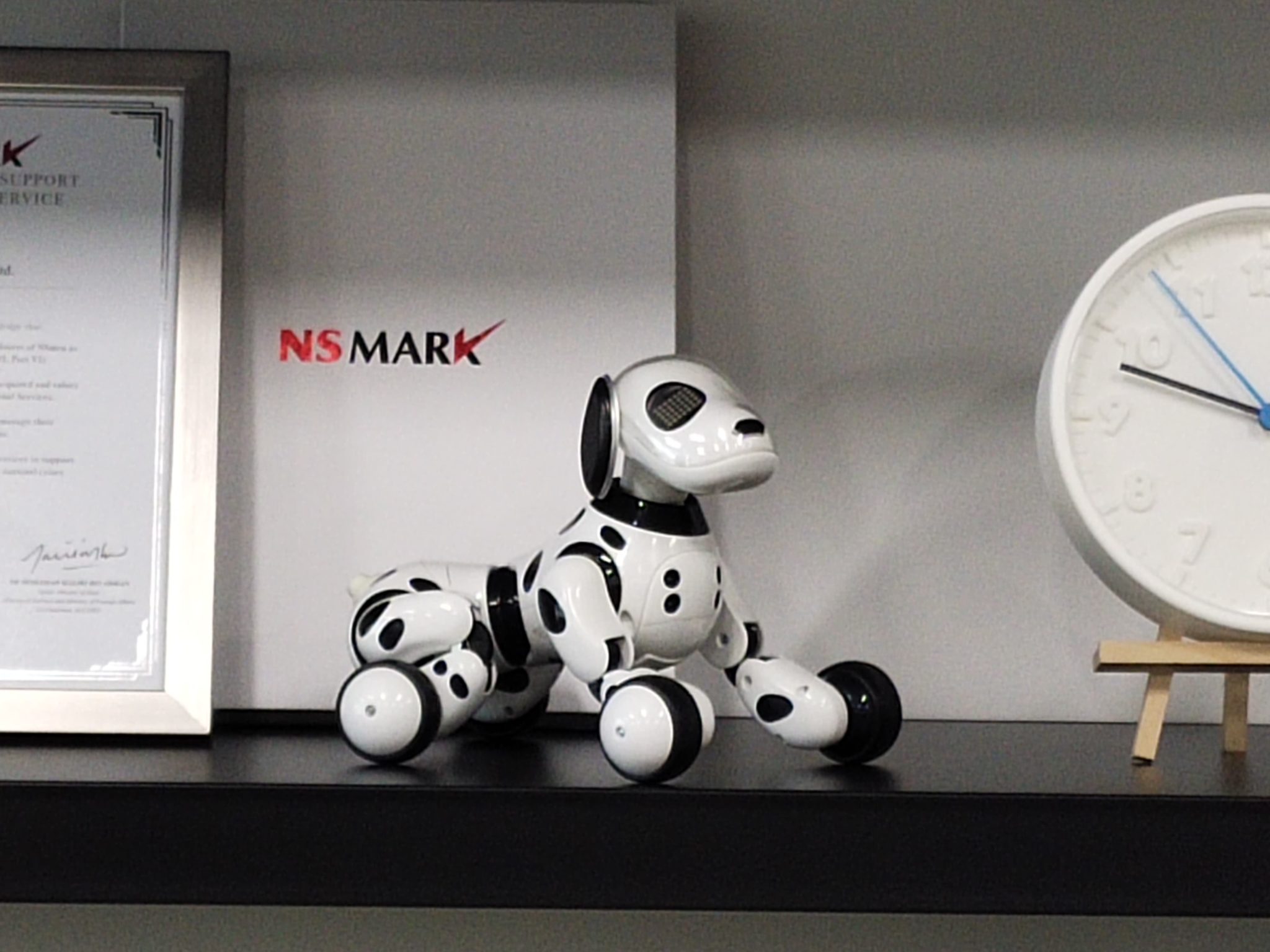 A robot dog and a clock on the shelf at 5x zoom