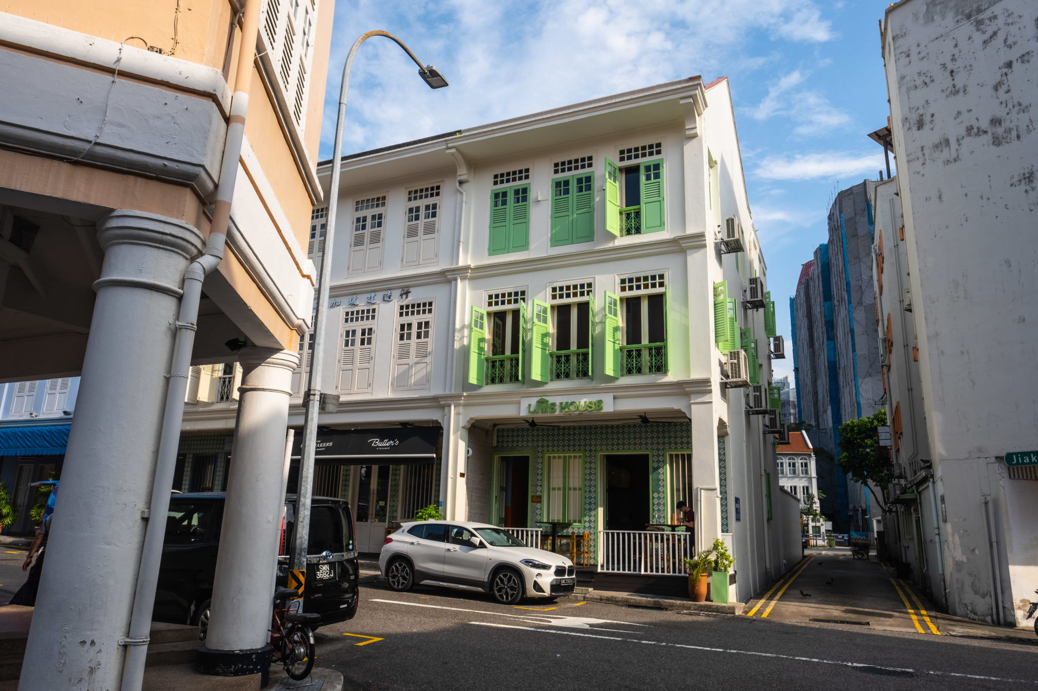 The pale shophouse with lime green windows on a Chinatown street