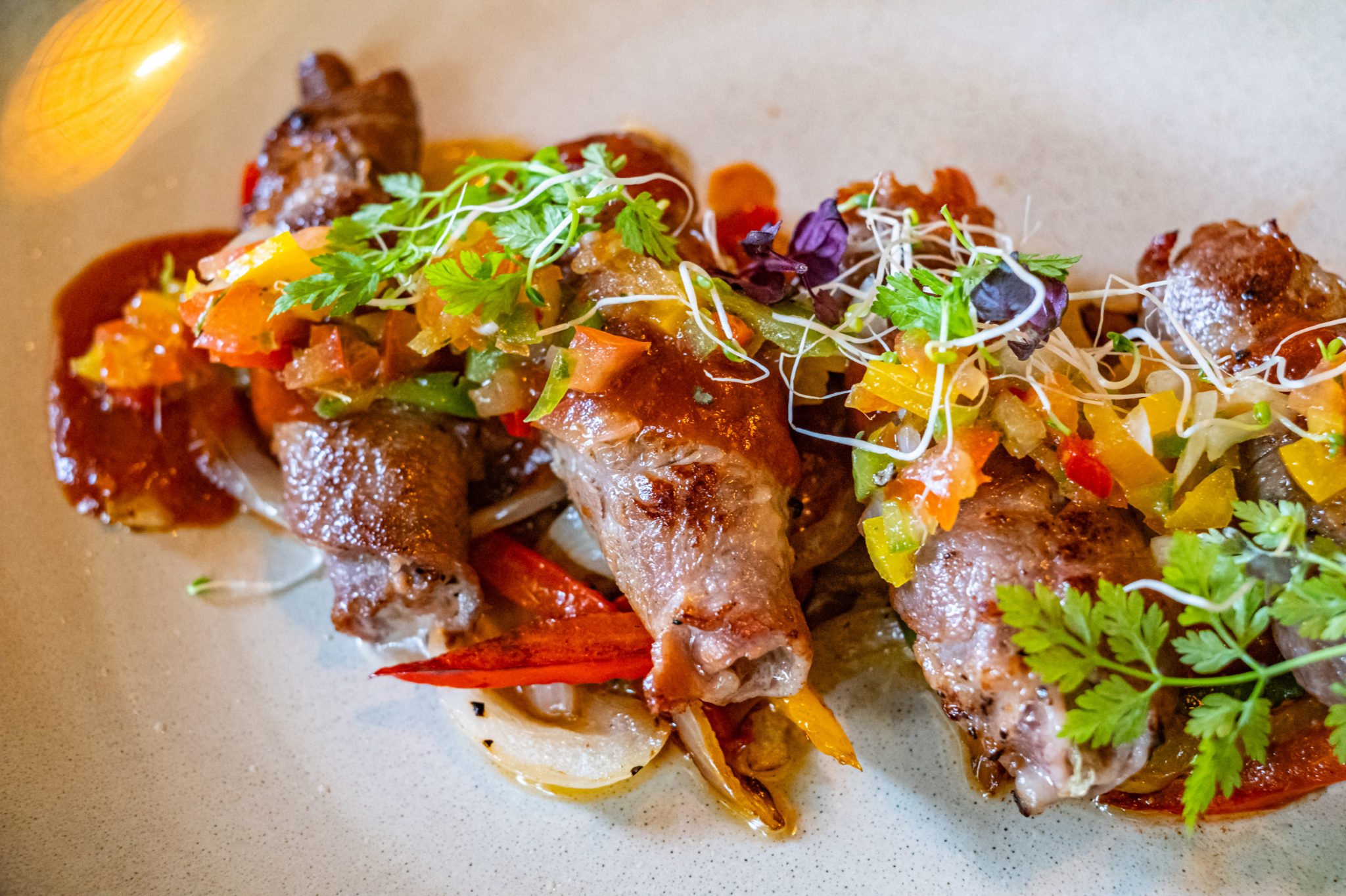 Rolled pork collar with salsa and microgreens on a plate