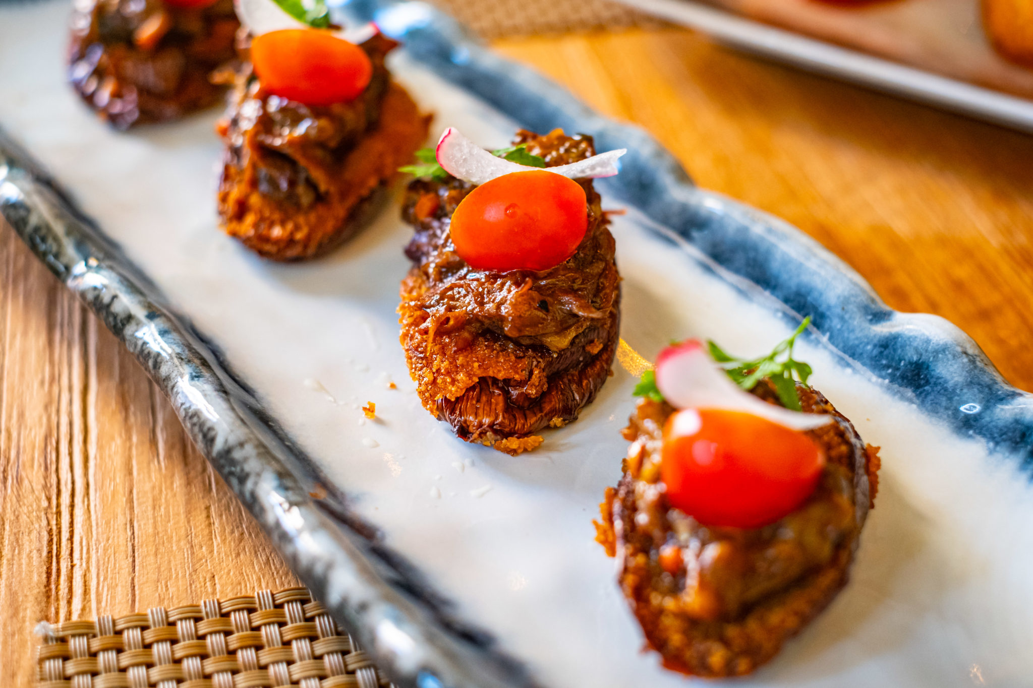 Breaded oxtail and eggplant bites topped with cherry tomato and radish