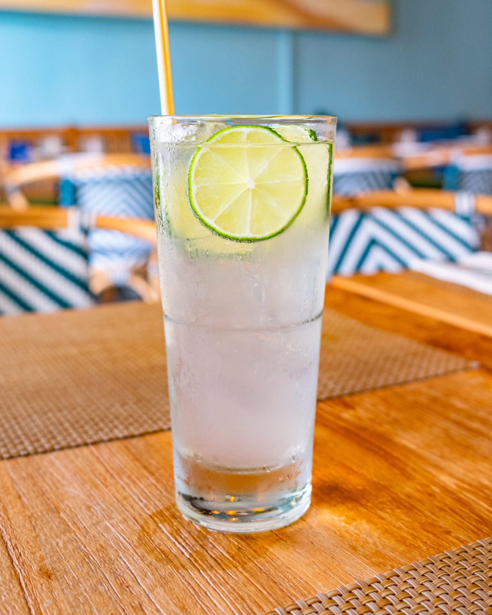 A tall Willemstad Collins with a lime wheel and straw
