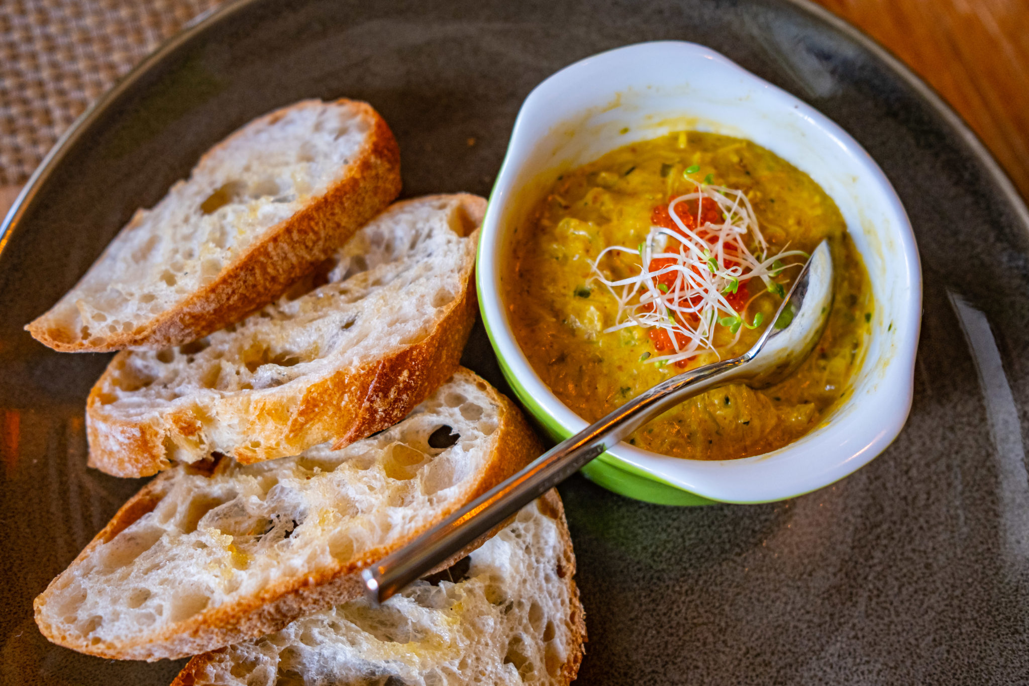 Slices of toast beside a bowl of curried potted crab
