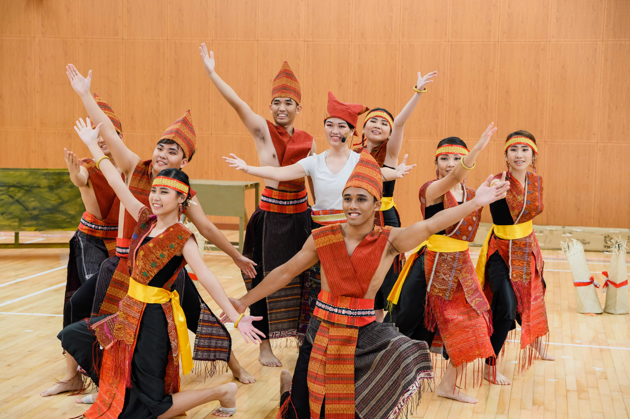 Cast members in traditional Batak costumes dancing with arms raised during a Nilanka rehearsal