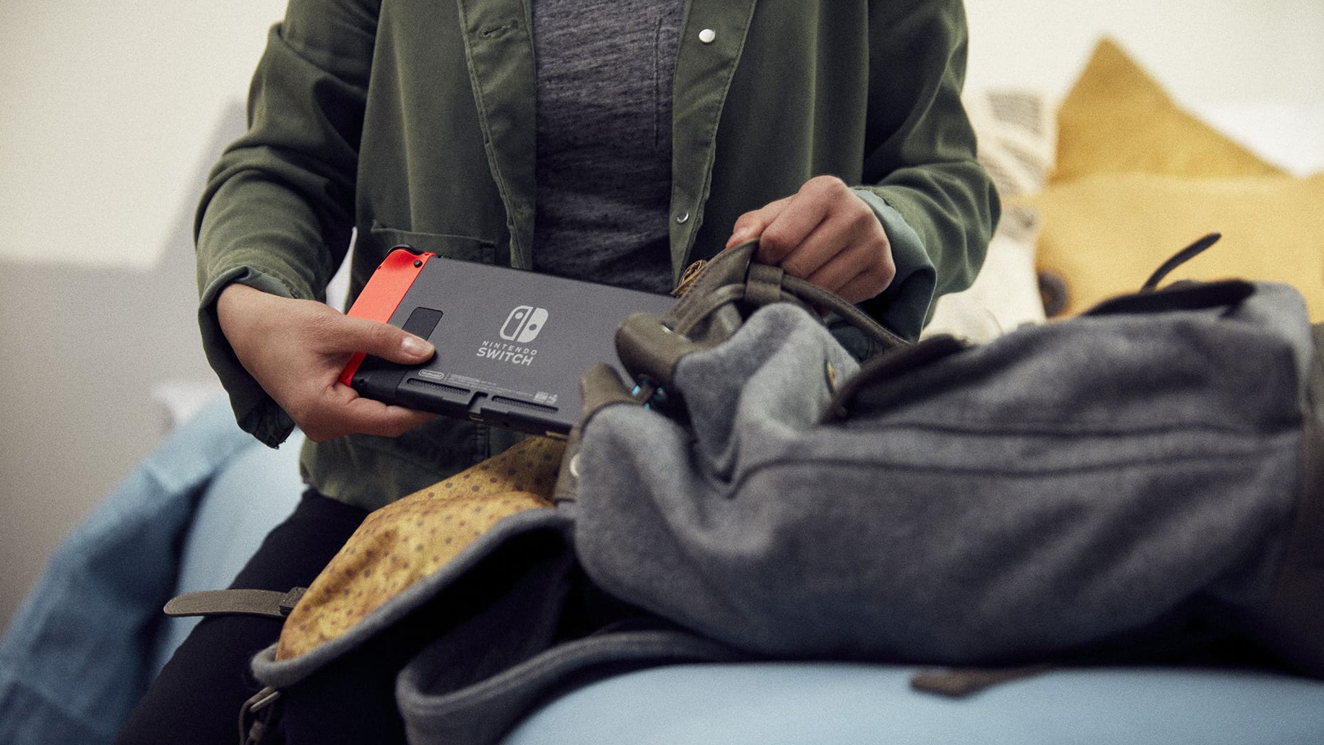 A person slipping a Nintendo Switch into a backpack