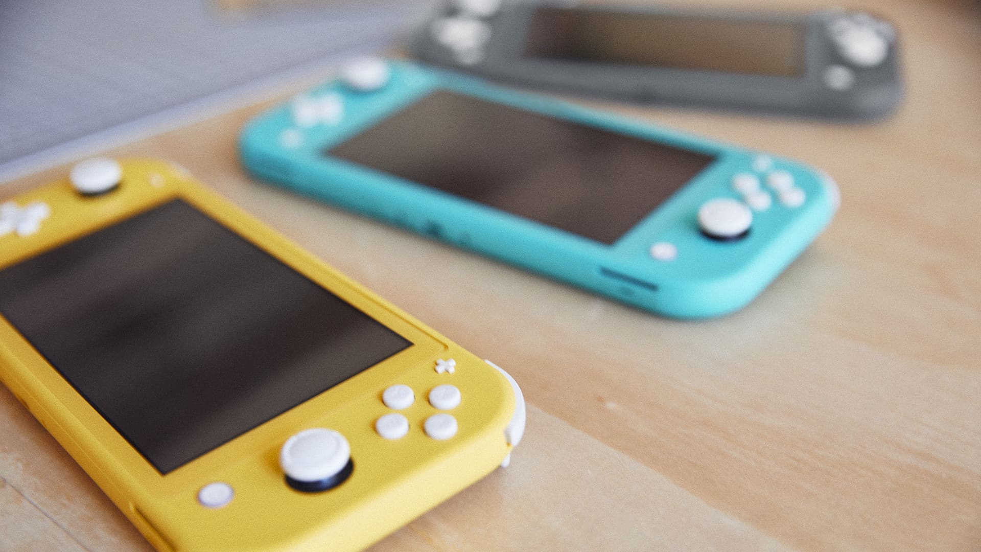 Yellow and turquoise Nintendo Switch Lite consoles on a table
