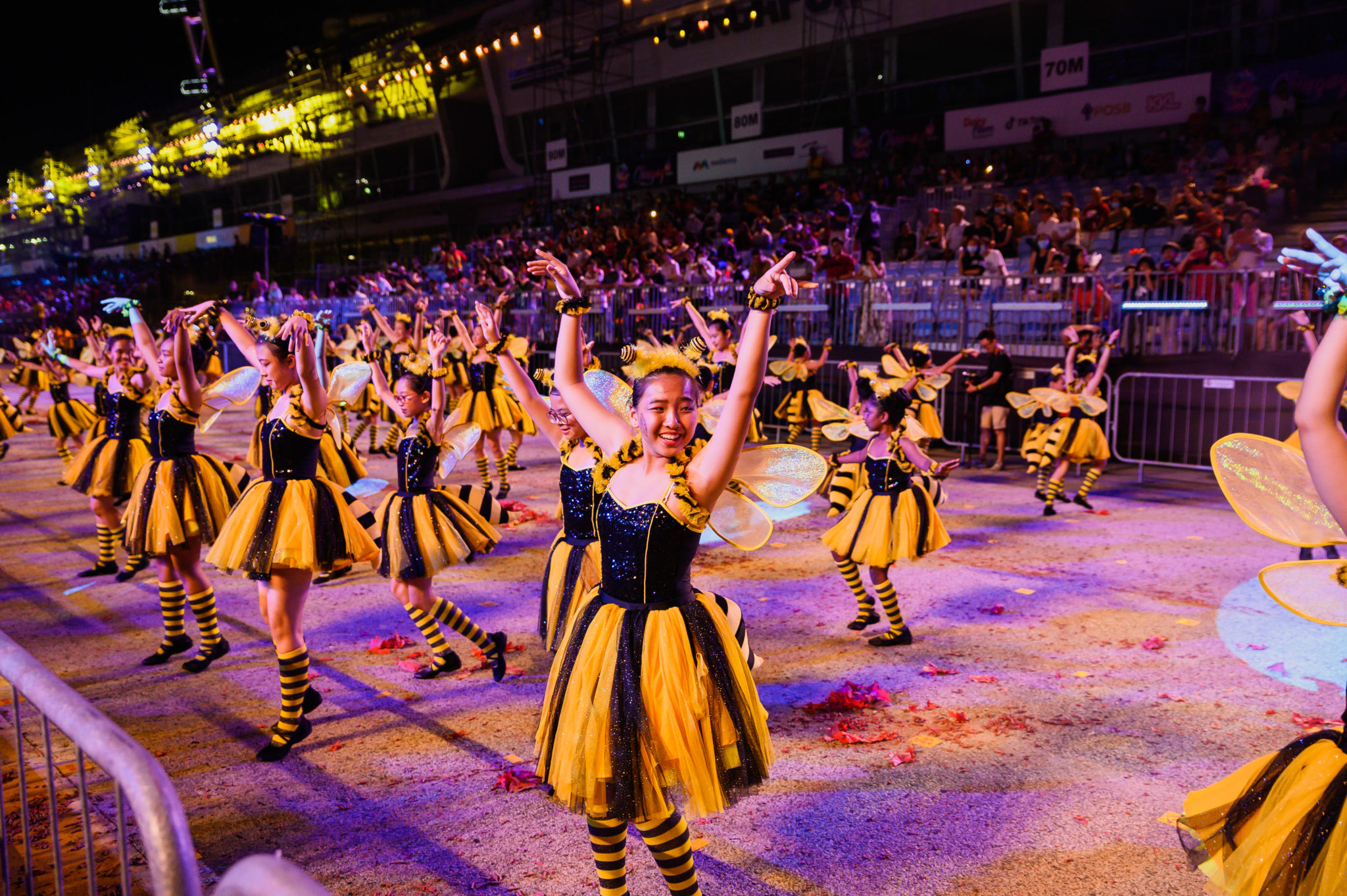 Dancers in black and yellow bee costumes performing in the street at Chingay