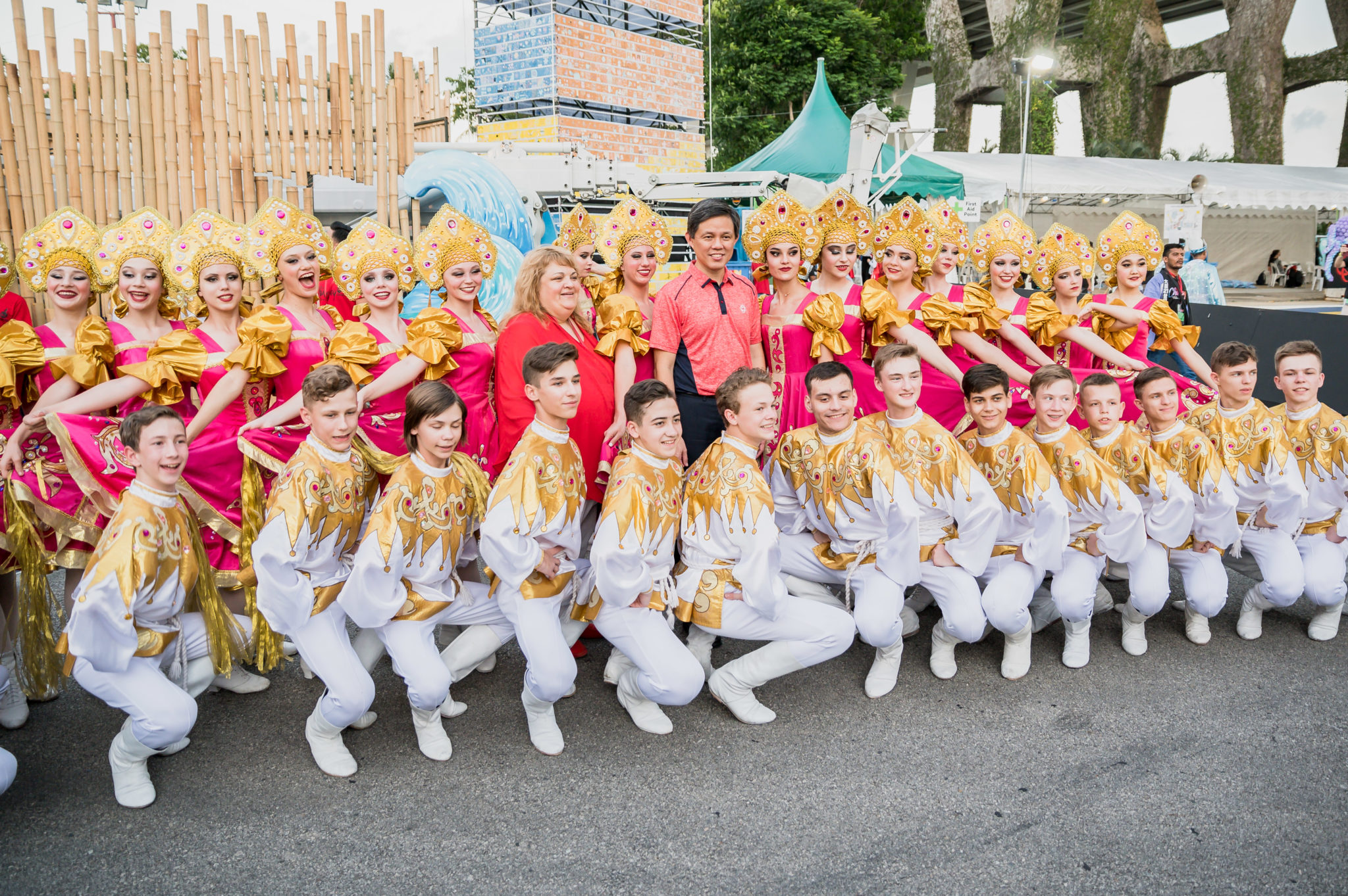 A group of performers in gold and white costumes posing together before the Chingay parade