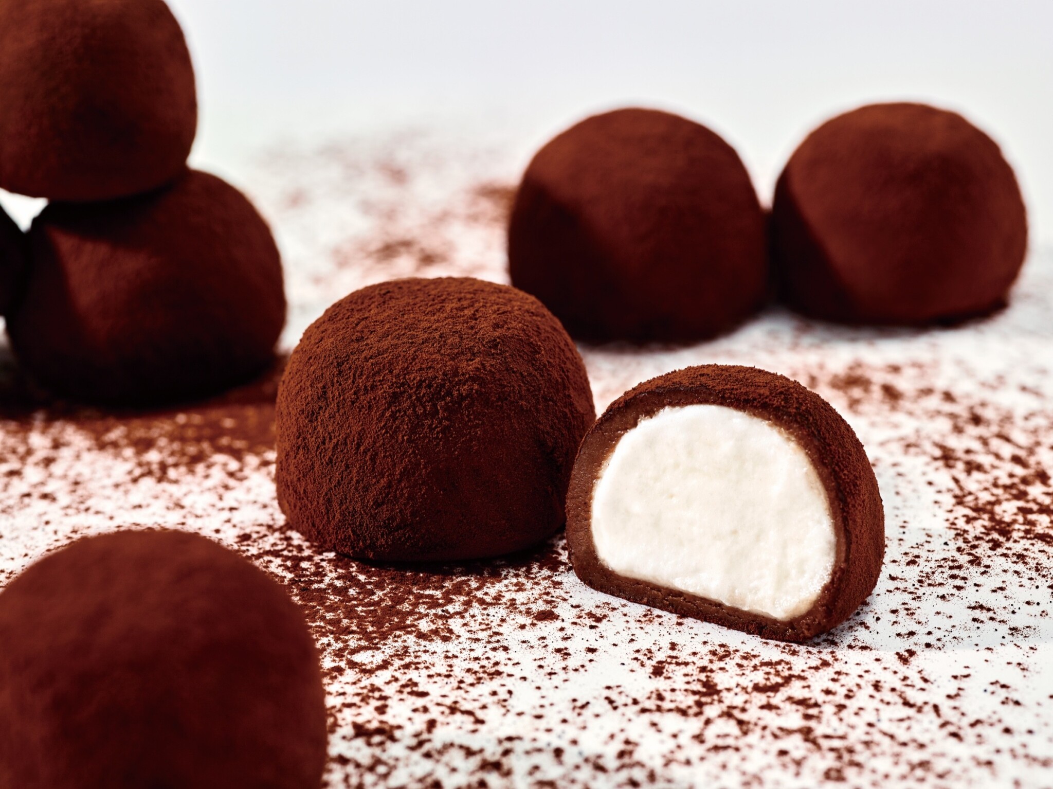 Cocoa-dusted chocolate balls include one cut open to reveal a pale cream centre.
