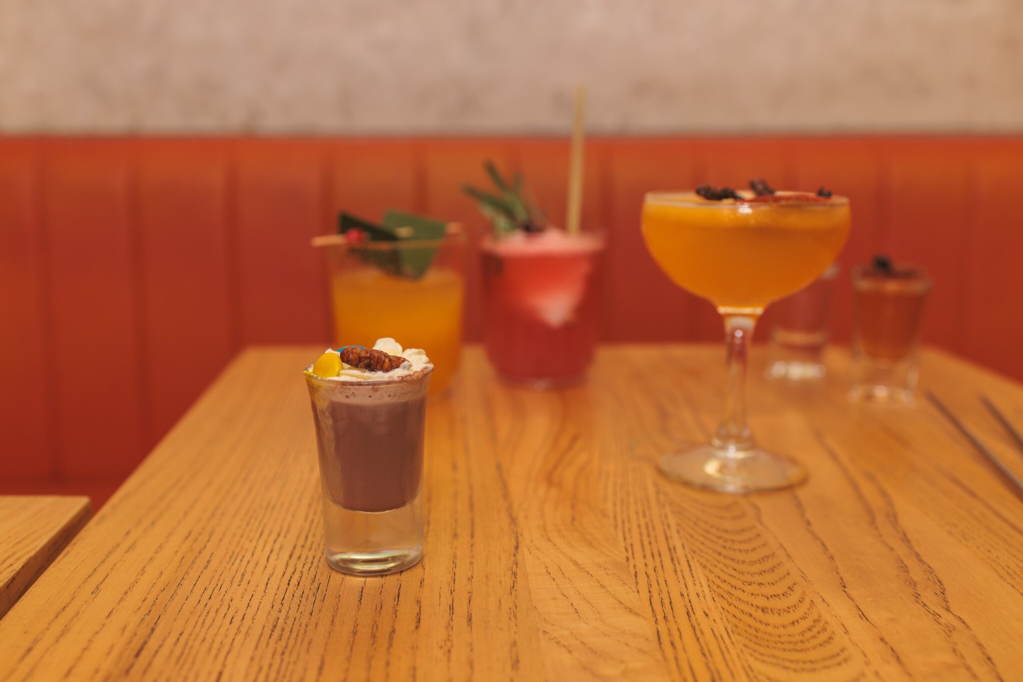 A row of colourful cocktails with unusual garnishes sits on a table.