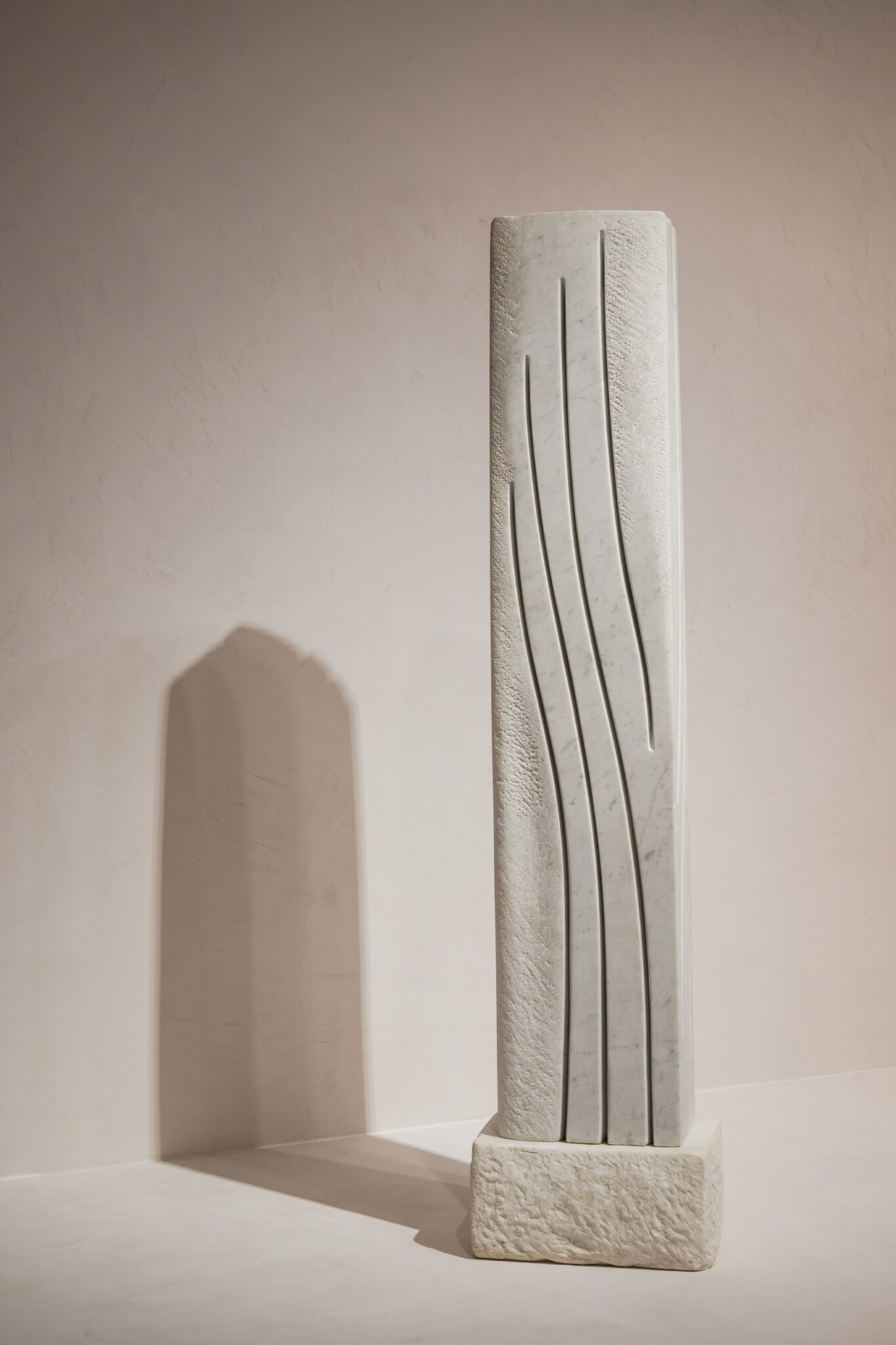 A pale stone sculpture has curved lines carved into its surface.