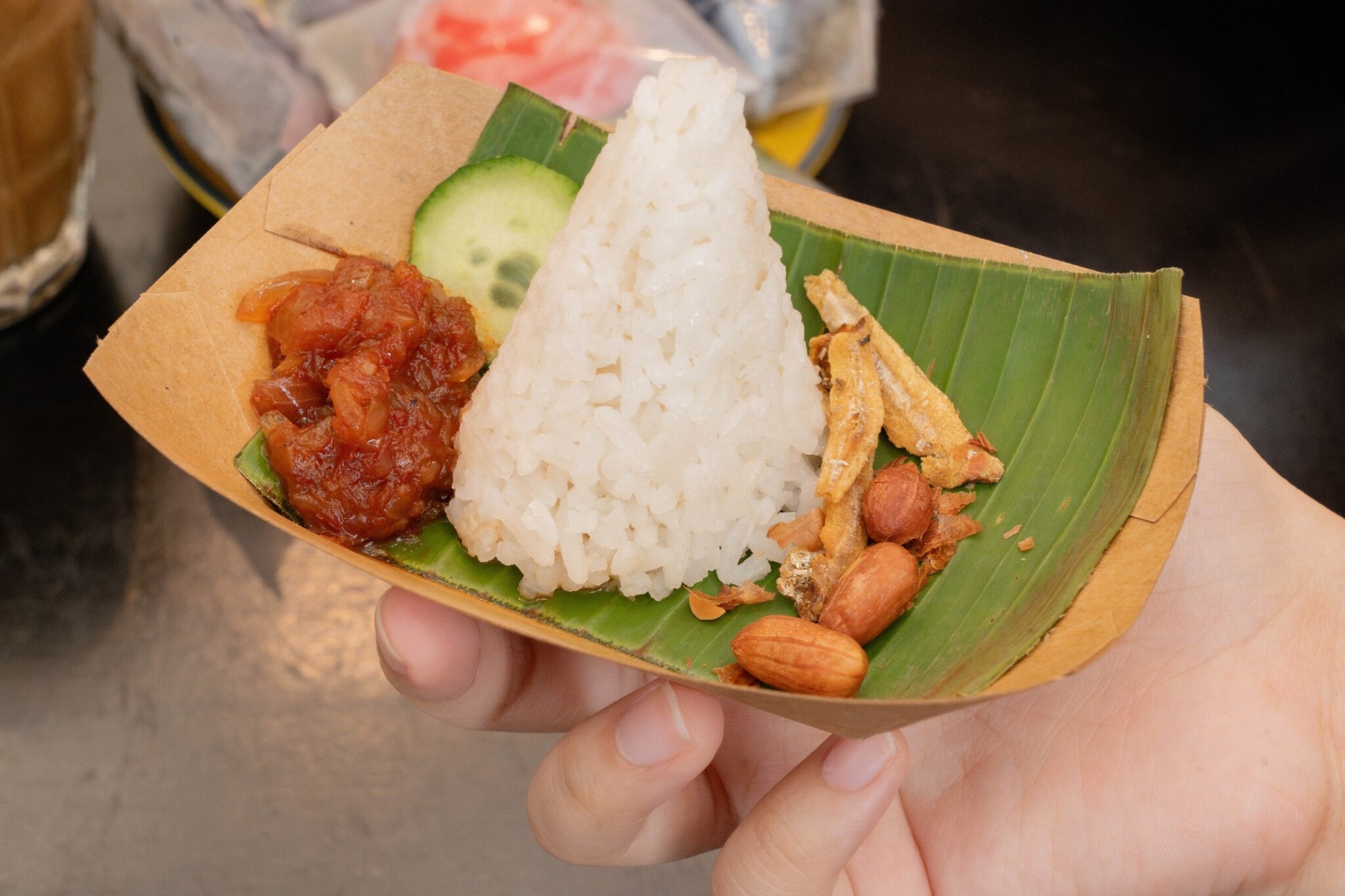 Nasi lemak with rice, egg and accompaniments sits on a banana leaf-lined tray.