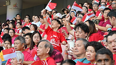 Crowd dressed in red waving Singapore flags inside Our Tampines Hub