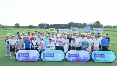 Junior golfers and coaches pose with handmade signs at the Junior Charity Classic