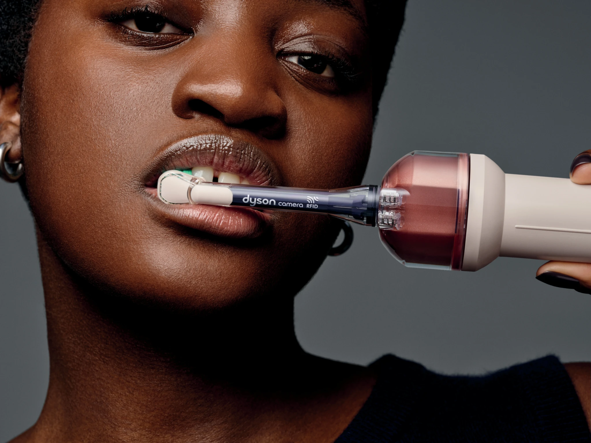 Dyson CameraJet toothbrush being used, with the camera-equipped brush head in a person's mouth