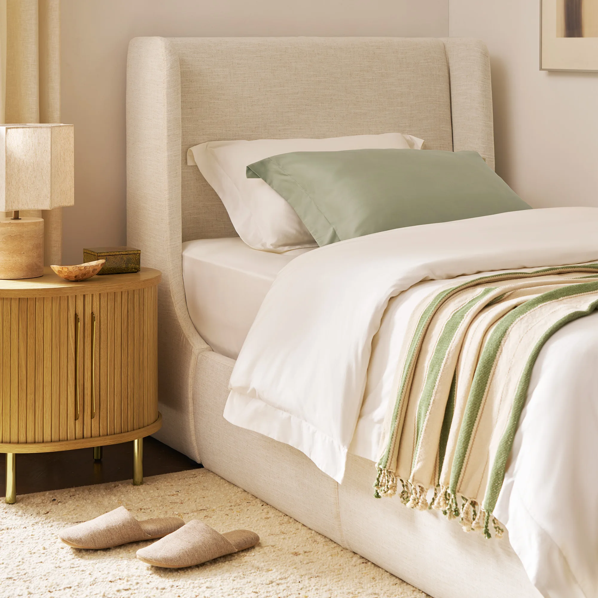 A bedroom styled with the Ayrie Mattress, white linens, and green accents