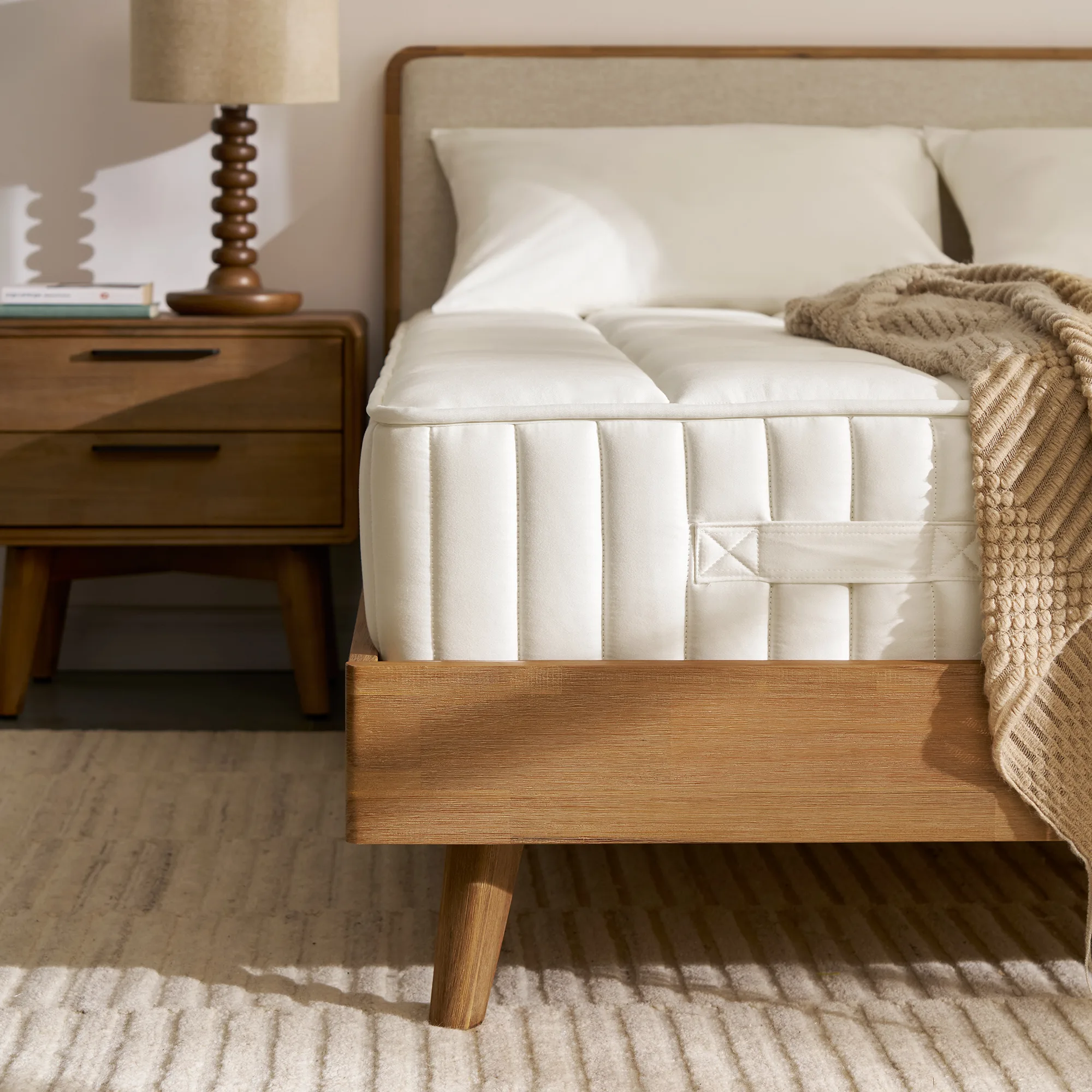 The Ayrie Mattress on a bed with pillows and a knit throw