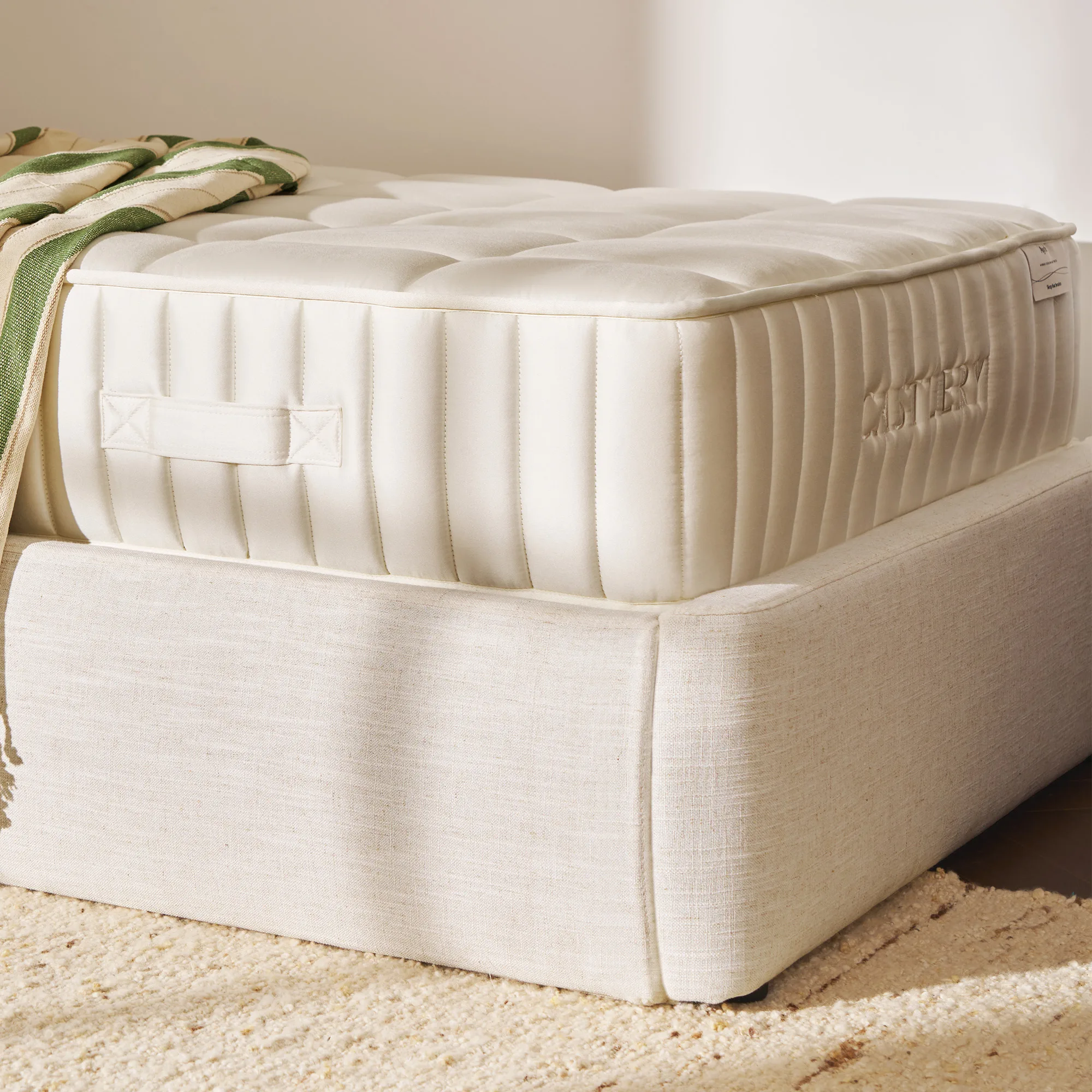 The Castlery Ayrie Mattress on a bed frame with quilted cream upholstery
