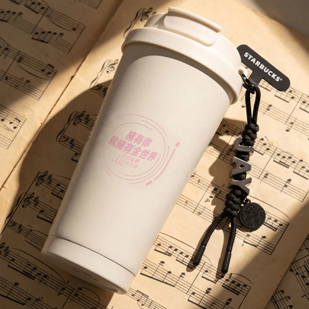 White Starbucks reusable cup with character lettering photographed on sheet music