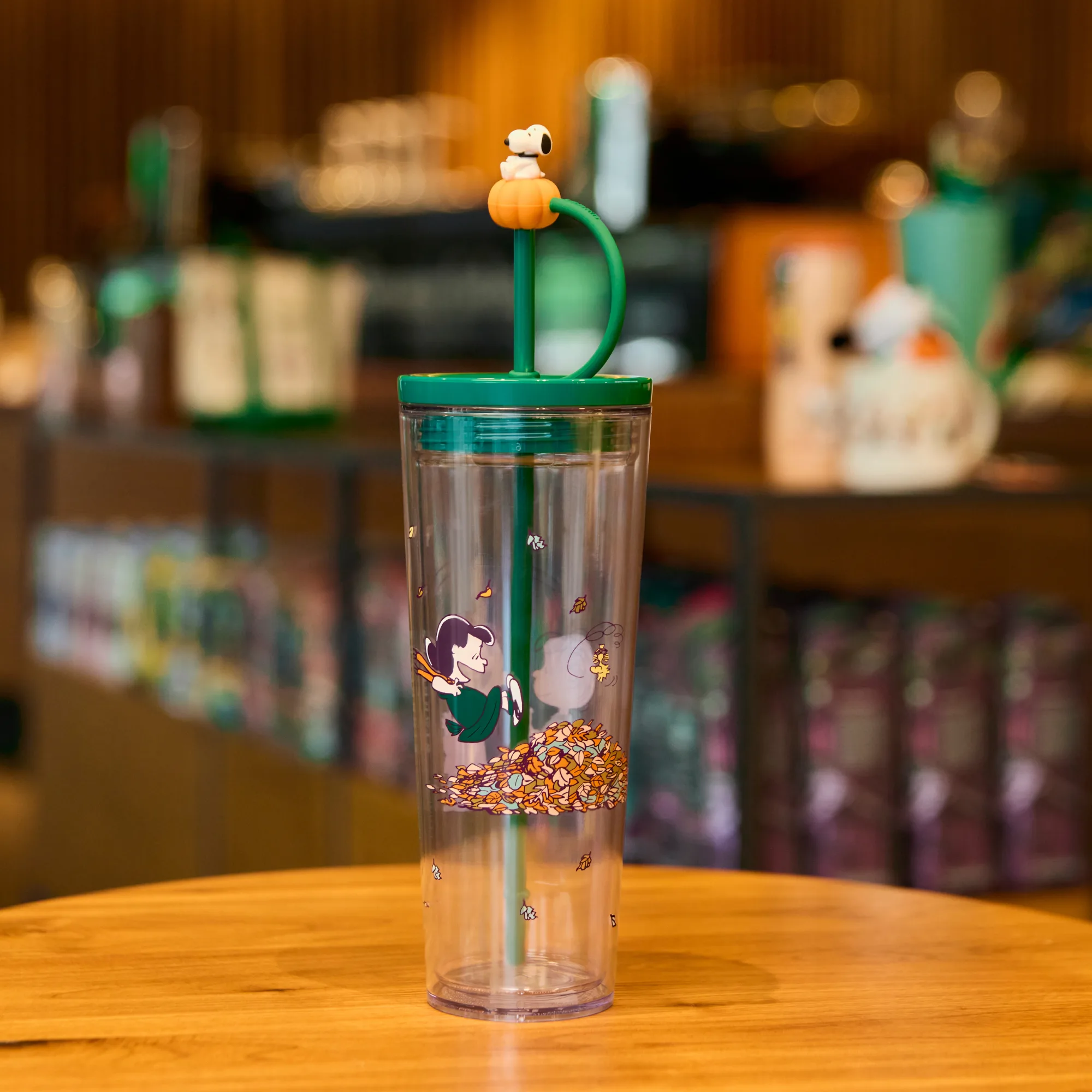 Clear tumbler with a small white bird topper perched on a green straw in a cafe setting