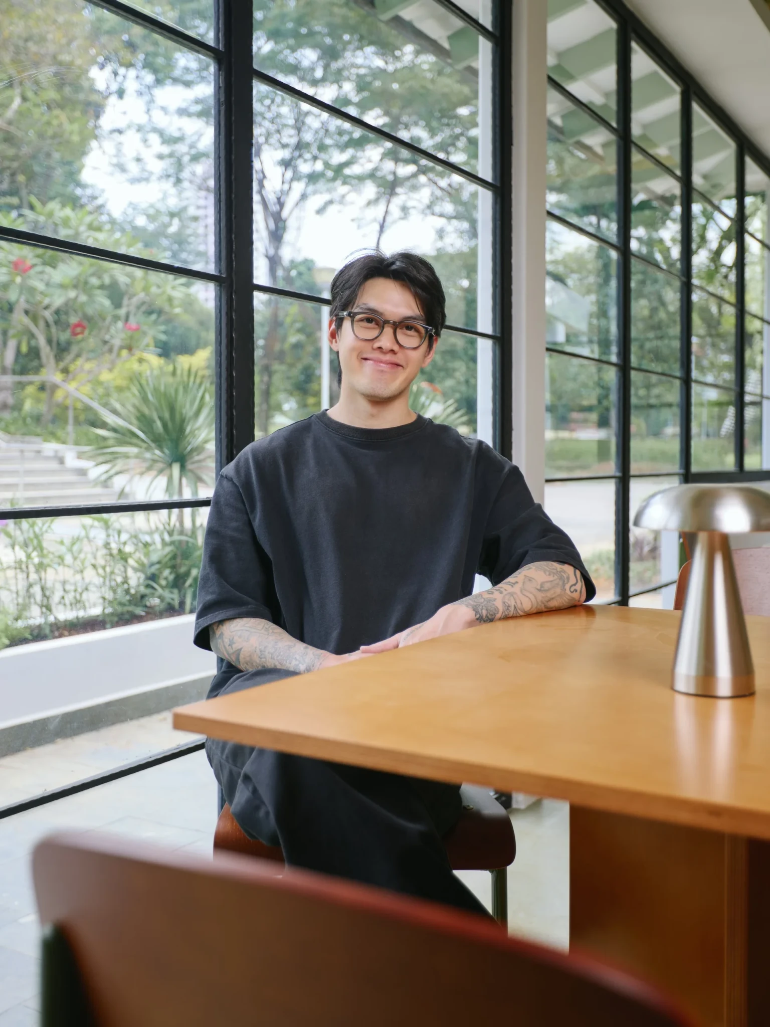 A Shared Table co-founder seated by the café windows overlooking Bishan-Ang Mo Kio Park