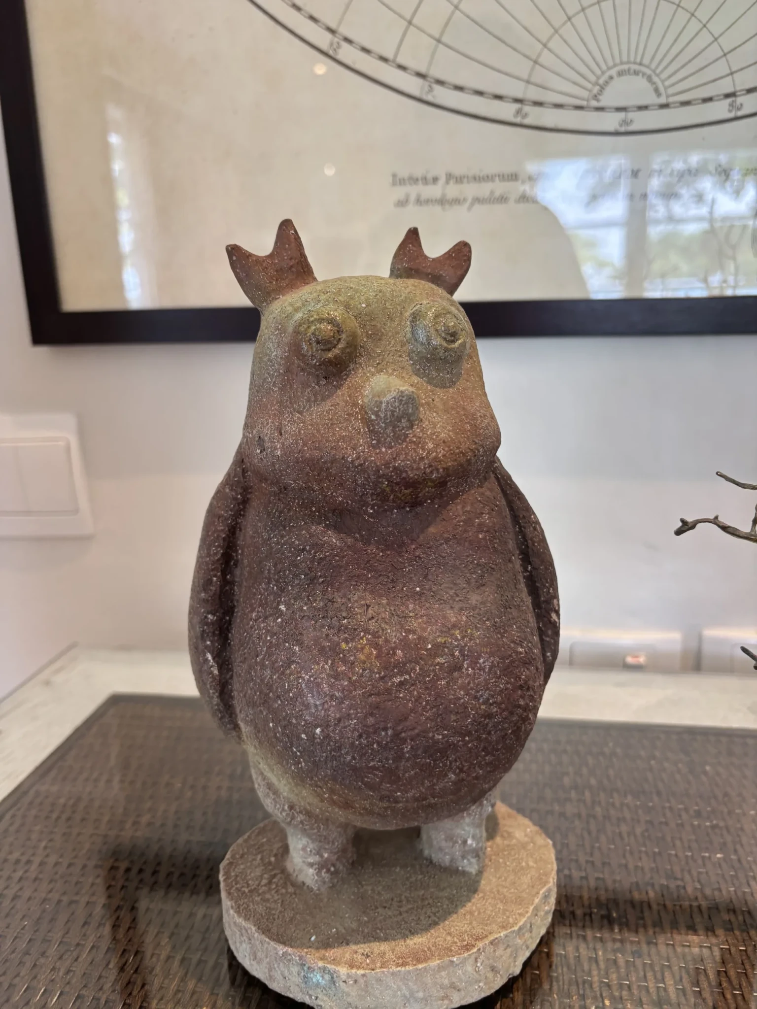 A brown stone owl sculpture with pointed ears on a stone base inside The Sanchaya