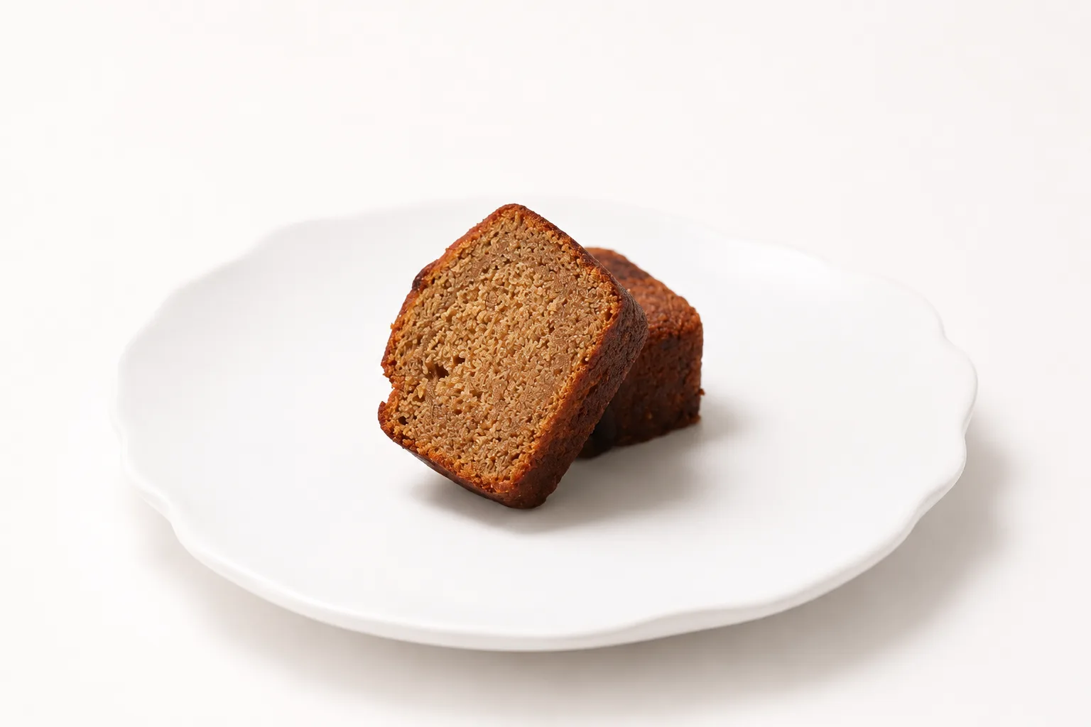 A slice of sticky date cake on a white plate