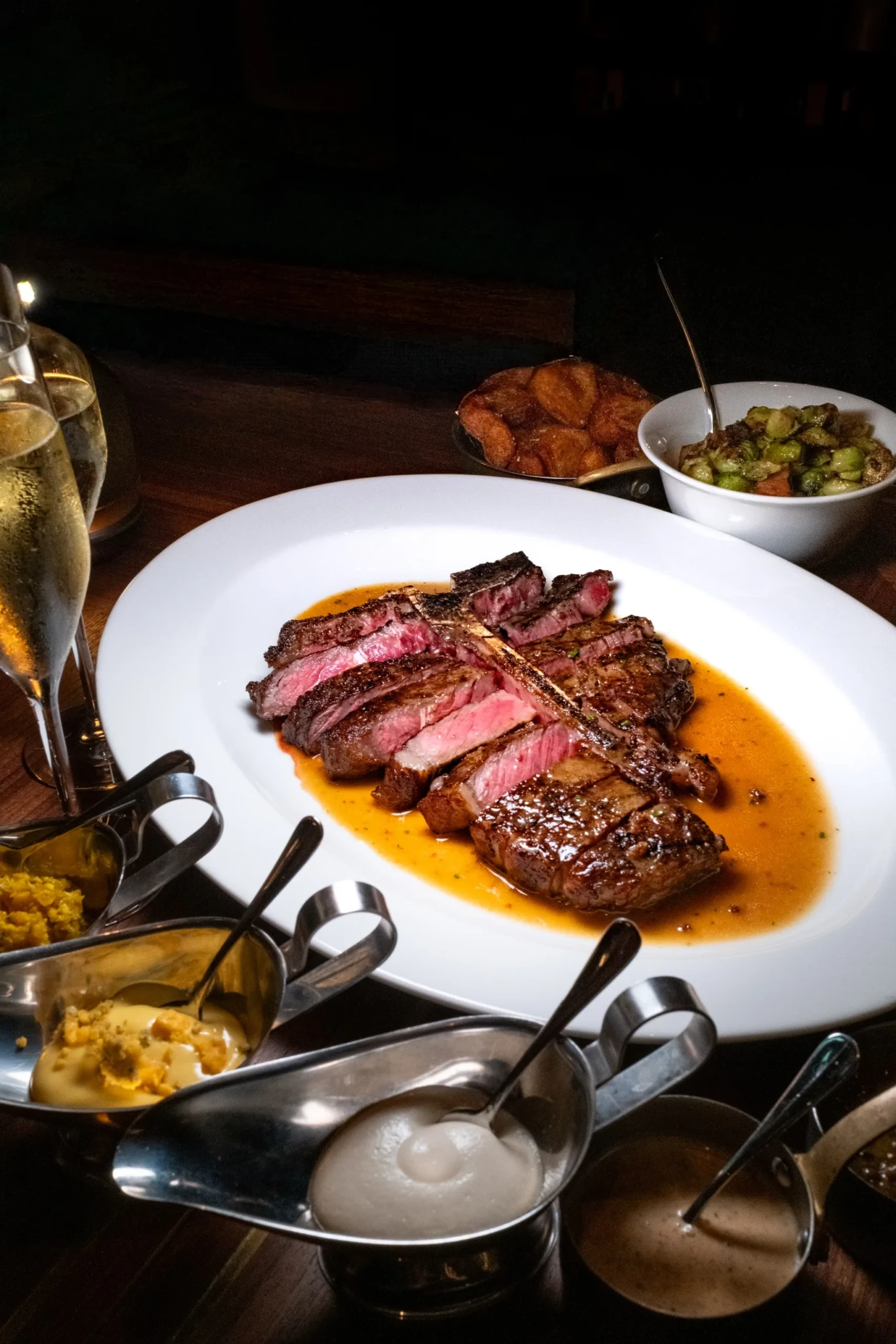 A sliced wood-fired steak served with caramelised sauce and roasted Brussels sprouts