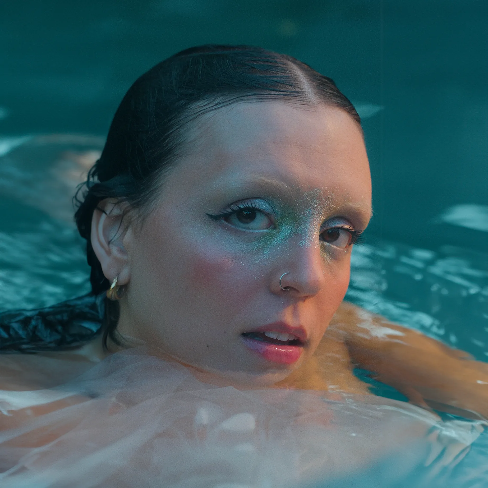 googly eyes standing in turquoise water wearing shimmering teal eyeshadow