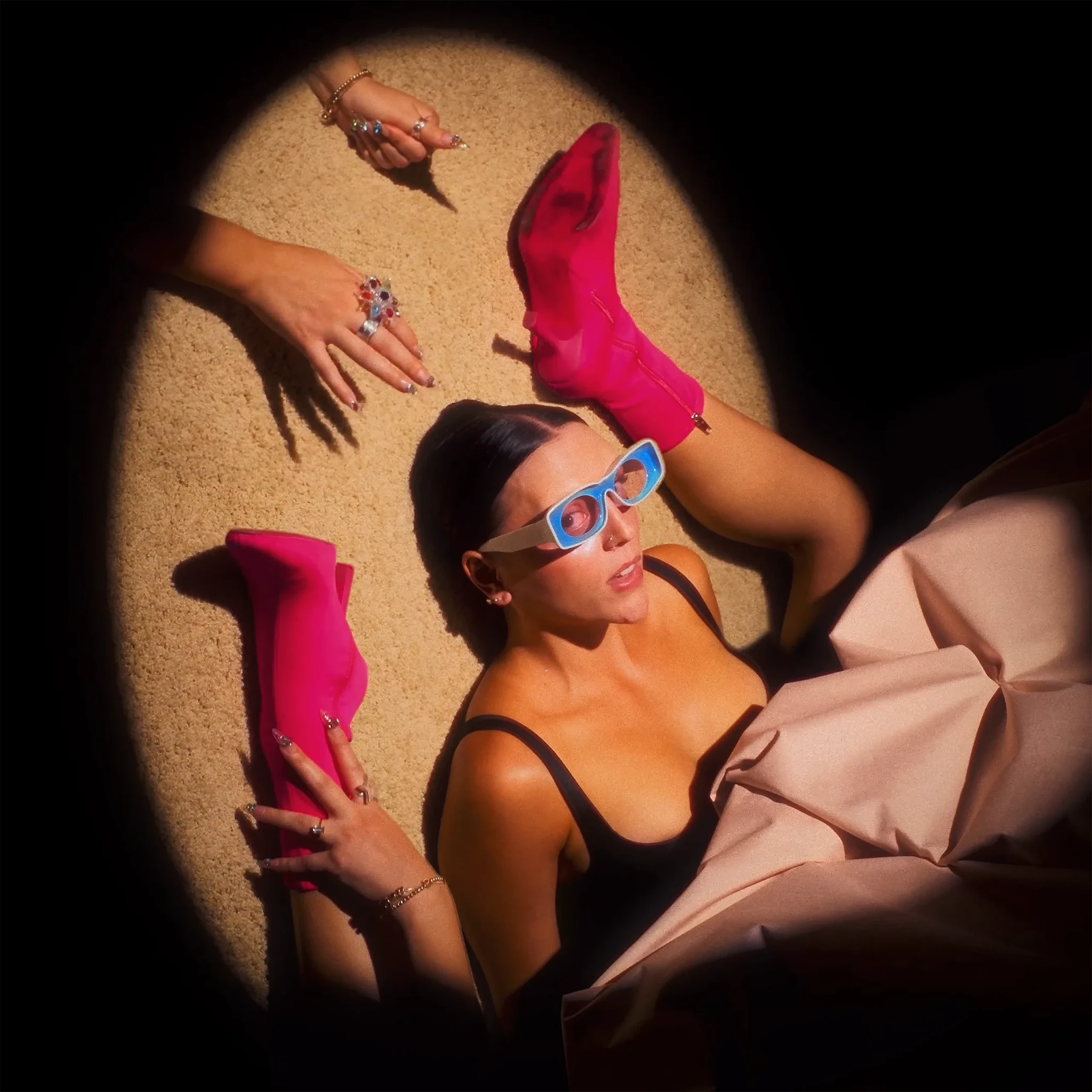 googly eyes on sand in oversized hot-pink trousers, a black bikini top, and blue sunglasses