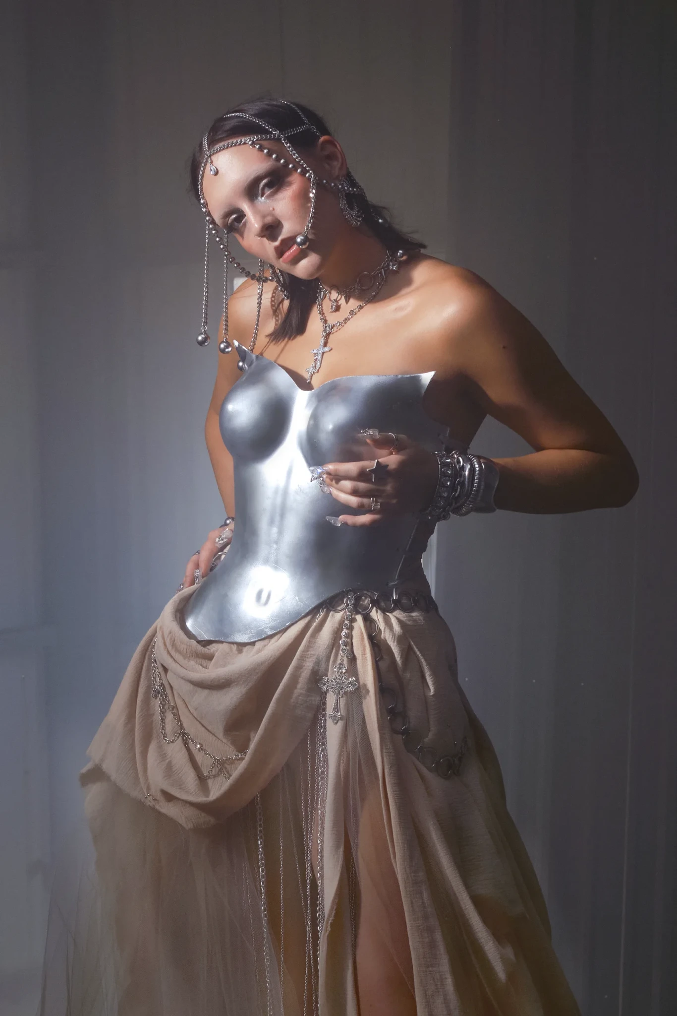 googly eyes in a sculptural silver breastplate with elaborate beaded eye ornaments against a neutral studio backdrop