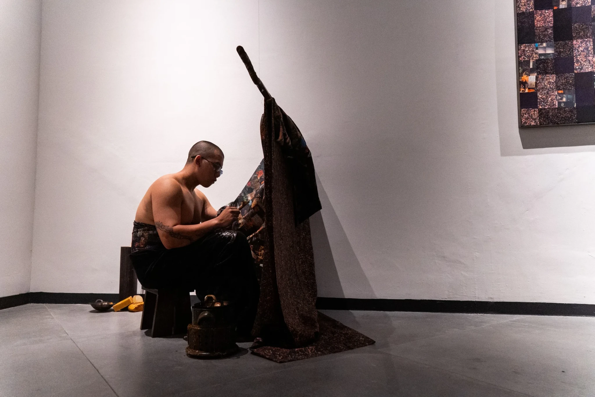 A performer interacting with a textured sculptural installation in a white gallery space
