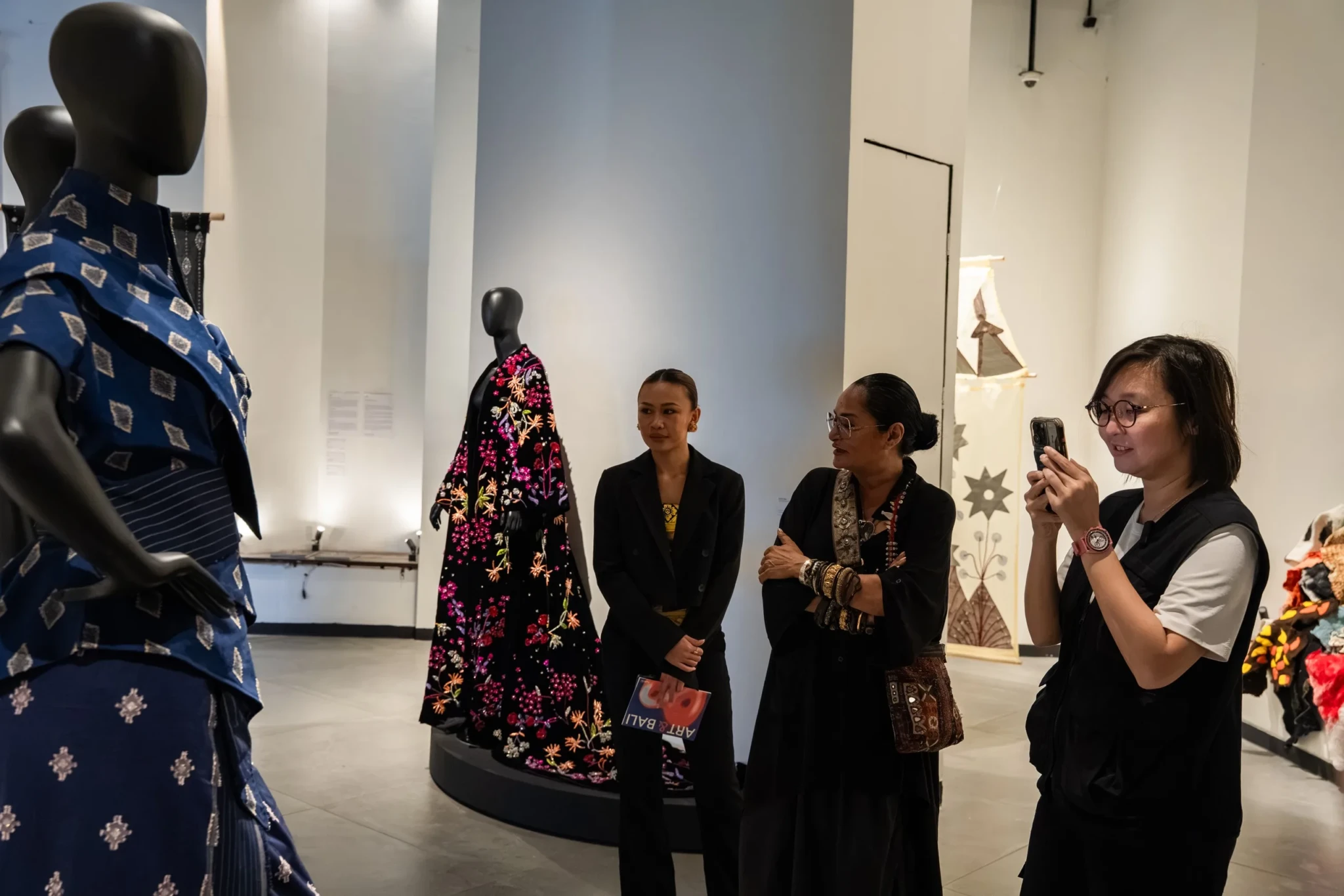 Visitors examining garments displayed on mannequins at the exhibition