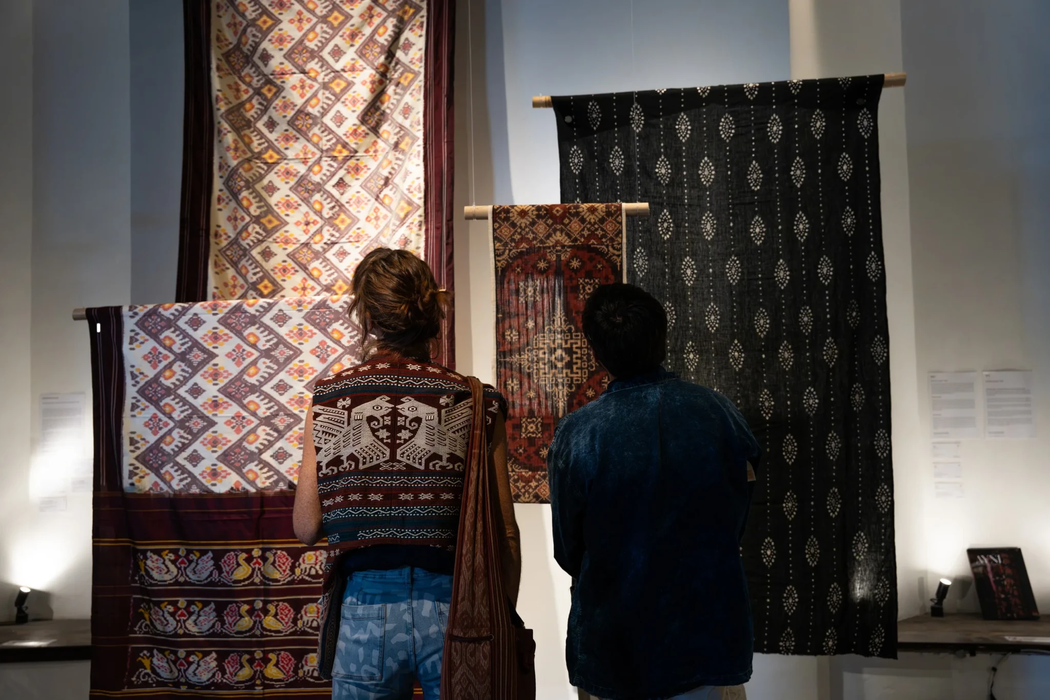 Visitors studying traditional textiles with geometric patterns on display