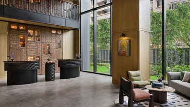 Lobby of Xi Zhe Wuxi with sculptural black seating and bronze-toned wall panels facing a planted courtyard