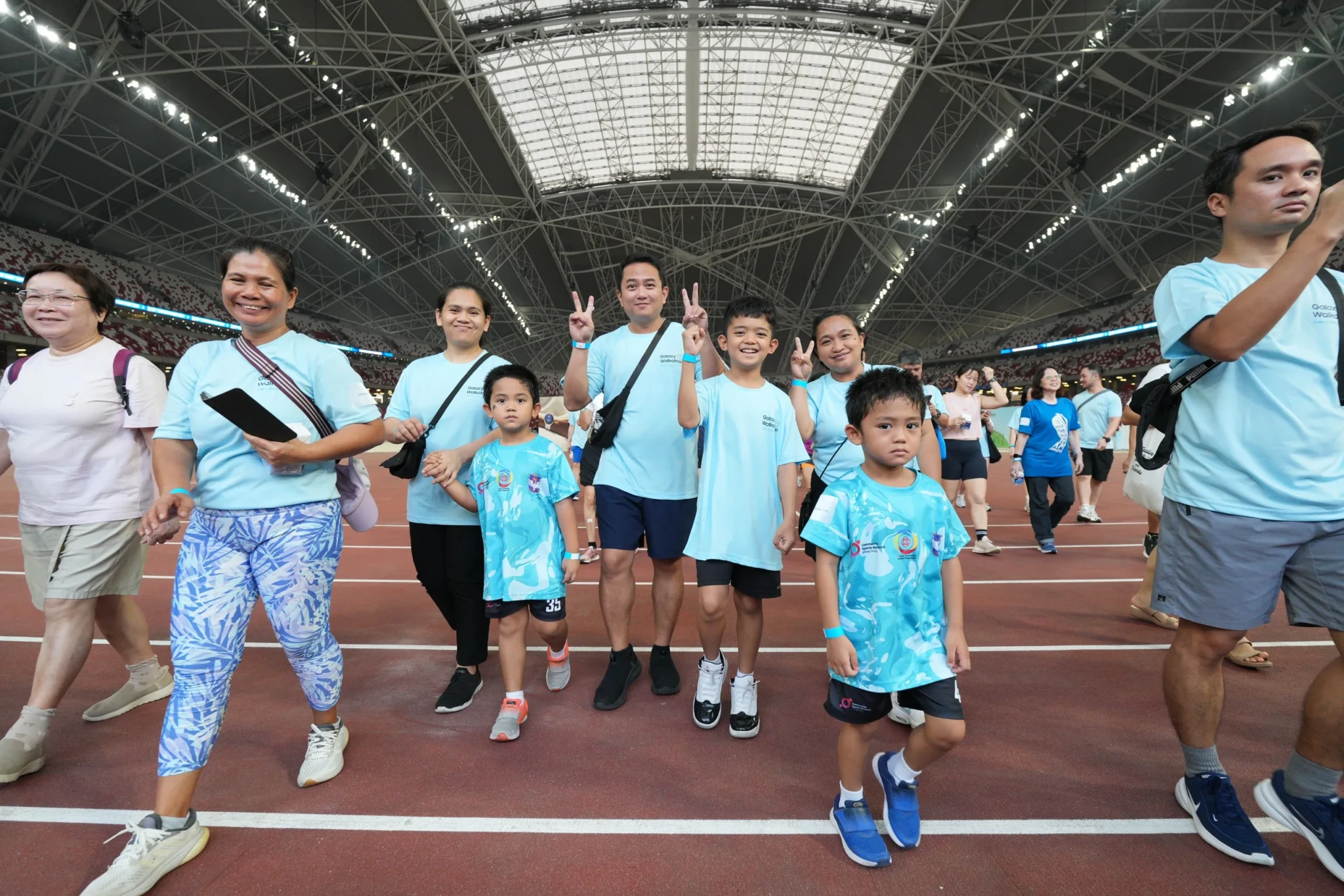 Participants in Galaxy Walkathon t-shirts celebrate at the National Stadium in The Kallang