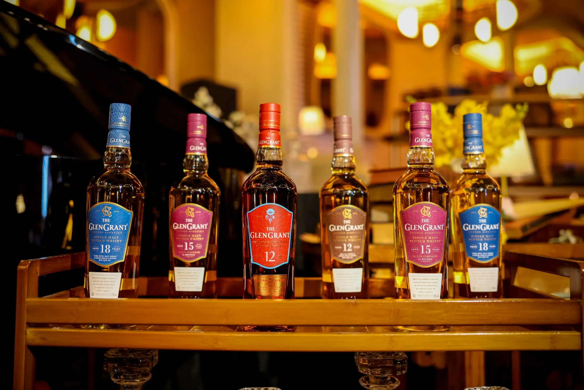 Bottles from The Glen Grant range lined up on a wooden shelf